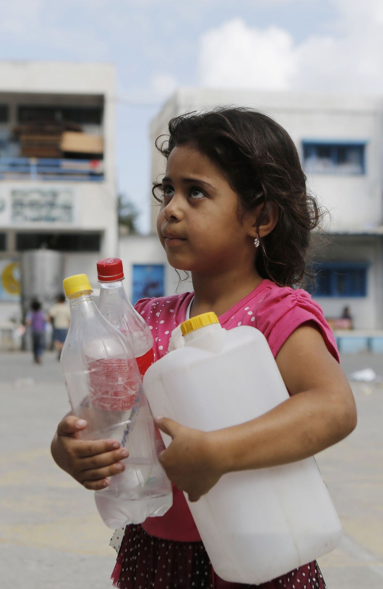Une fillette réfugiée à Gaza City transporte des bouteilles d'eau