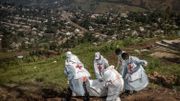 Des membres de la Croix-Rouge congolaise transportent des sacs mortuaires contenant des restes humains lors d’un enterrement de masse pour les victimes des affrontements dans l’est de la République démocratique du Congo au cimetière de Musigiko à Bukavu l