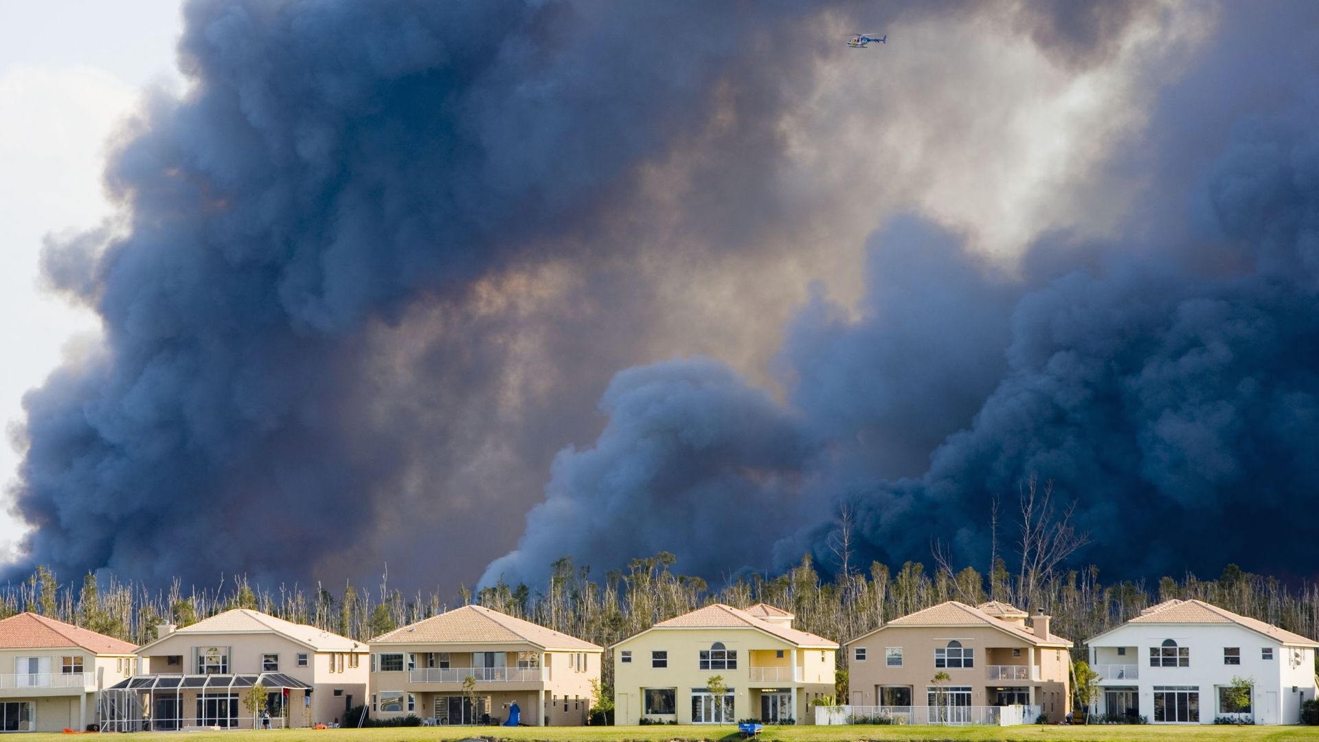 Un hélicoptère survole la fumée d'incendies à proximité d'habitations en Floride.