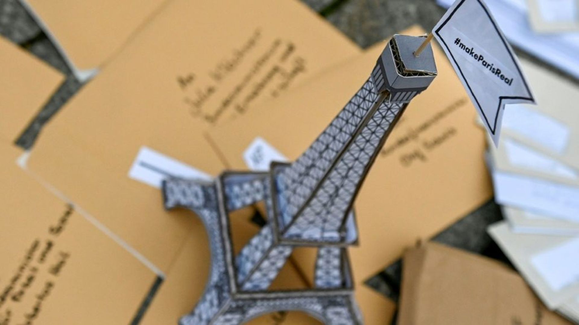Une tour Eiffel en carton couronnée d'un drapeau: "Fais en sorte que Paris devienne une réalité" faite partie d'une installation posée par des activistes face à la porte de Brandenburg à Berlin le 11 décembre pour marquer les 5 ans de l'Accord de Paris su