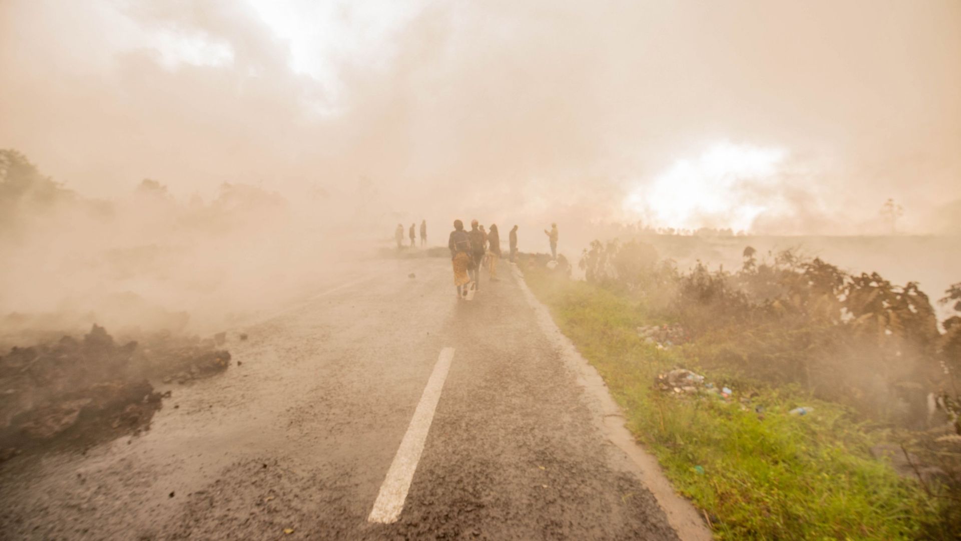 Des habitants marchent à travers les fumées du volcan