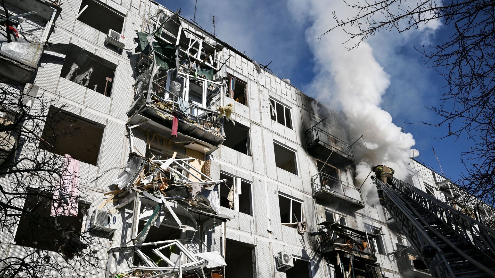 Des pompiers travaillent sur un incendie dans un bâtiment après des bombardements sur la ville de Tchouguiv, dans l’est de l’Ukraine, le 24 février 2022.