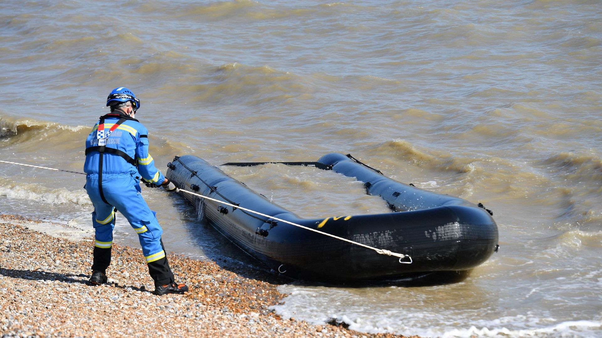 Des membres des garde-côtes britanniques retirent un bateau gorgé d'eau et abandonné, qui s'était échoué sur une plage de Lydd on Sea dans le sud-est de l'Angleterre le 8 septembre 2021.