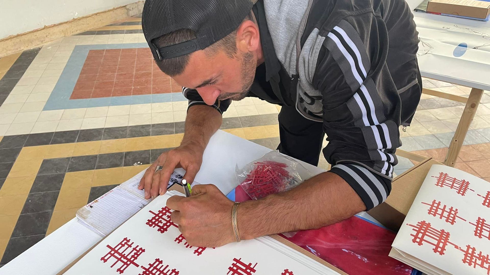 L’artiste Manu Bayon en train de signer la lithographie qu’il a créée à l’occasion de la triennale