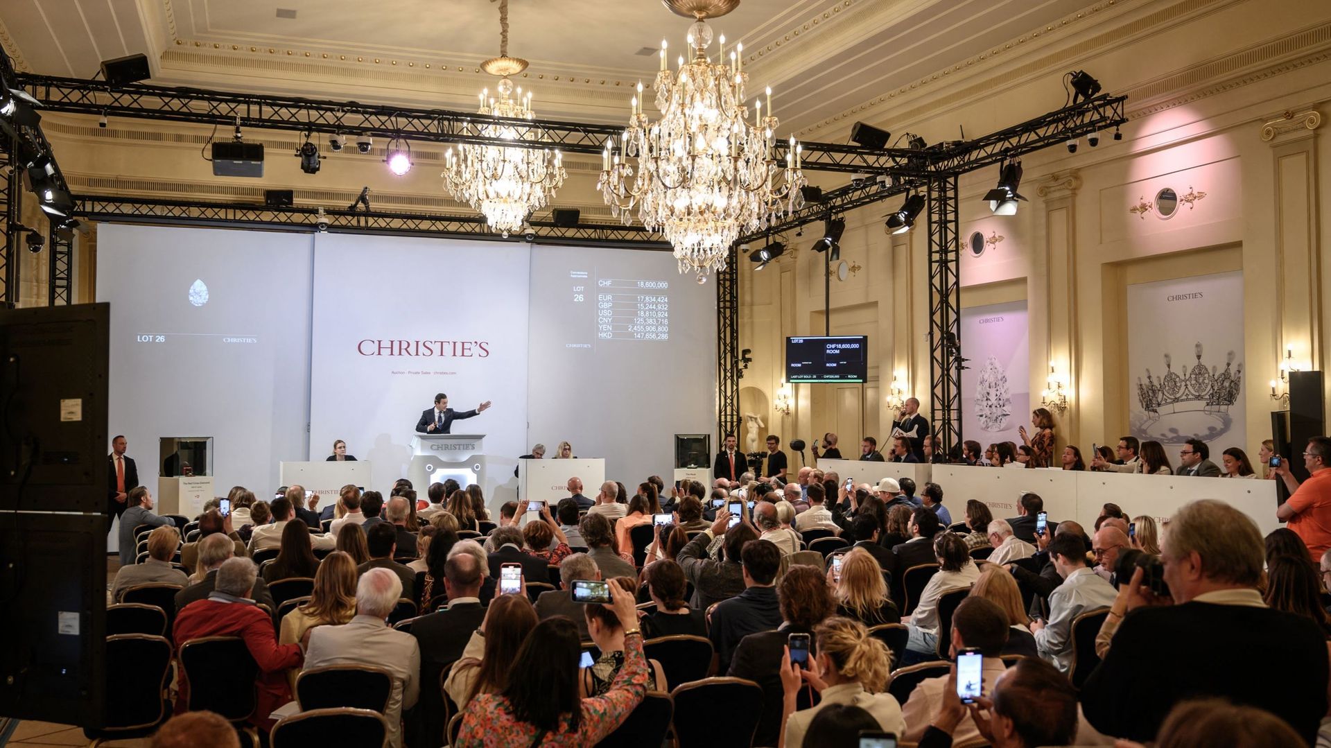 Rahul Kadakia (C), commissaire-priseur de Christie's, fait un geste pendant la vente de "Magnificent Jewels", le plus gros diamant blanc jamais vendu aux enchères à Genève, le 11 mai 2022.