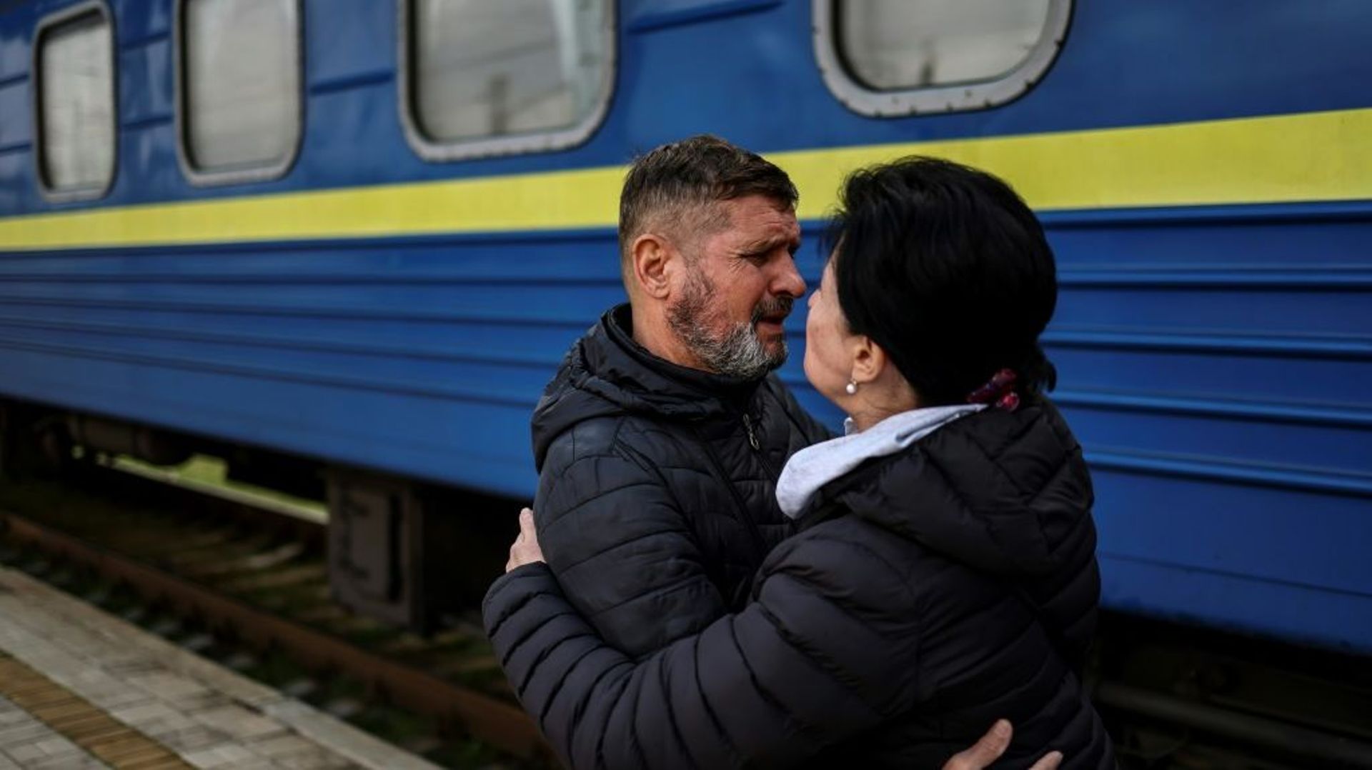 Un homme embrasse sa femme qui va prendre le train à la gare de Sloviansk, pour quitter l'Est de l'Ukraine en guerre, le 12 avril 2022