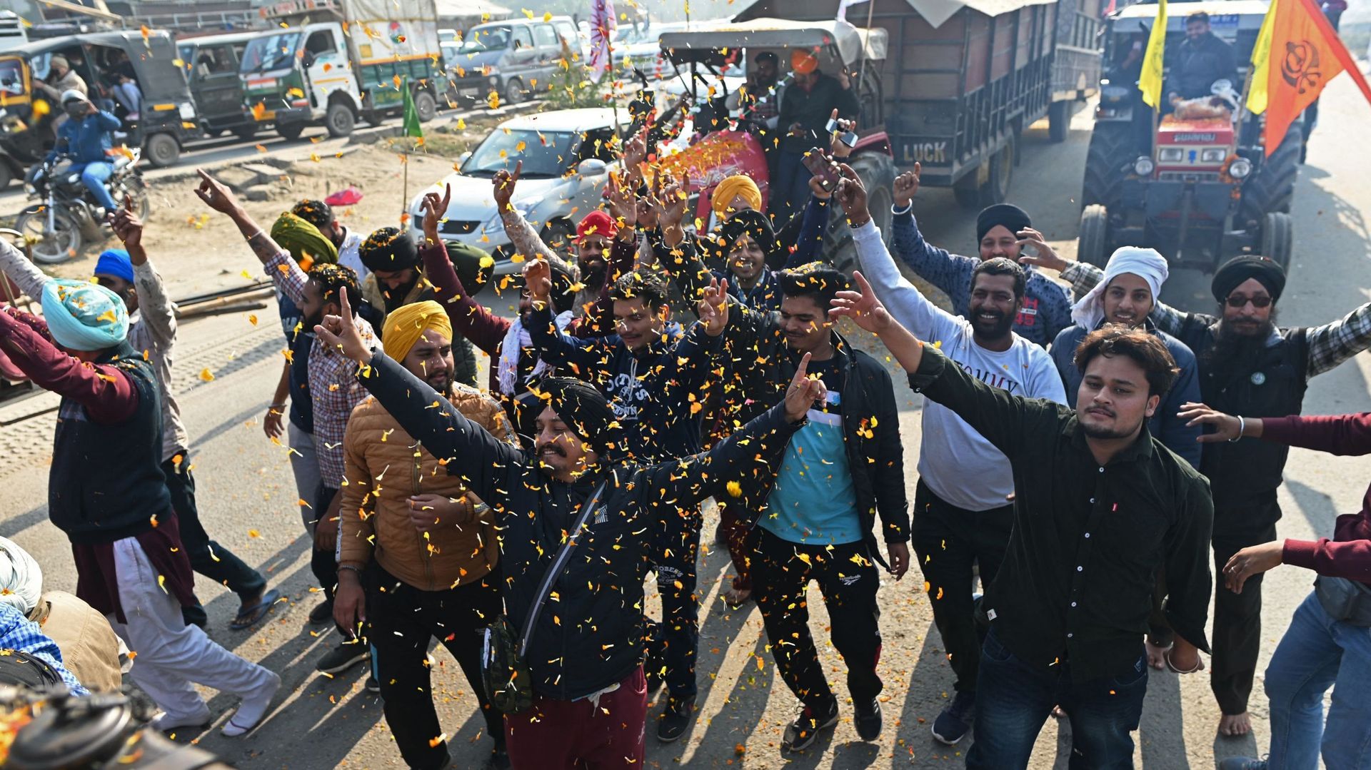 Des agriculteurs se réjouissent en quittant le site de protestation à la frontière de l'État de Delhi-Haryana à Singhu, le 11 décembre 2021, alors que les agriculteurs rentrent chez eux depuis la périphérie de Delhi après une année de protestation contre 