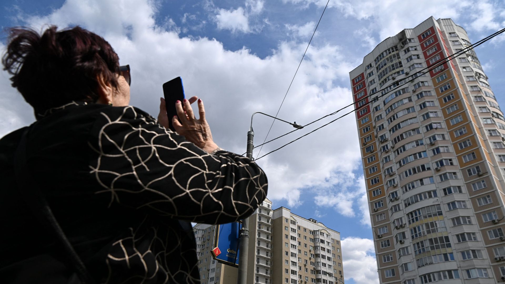 Une femme prend une photo d’un immeuble de plusieurs étages endommagé après une attaque de drone à Moscou le 30 mai 2023.