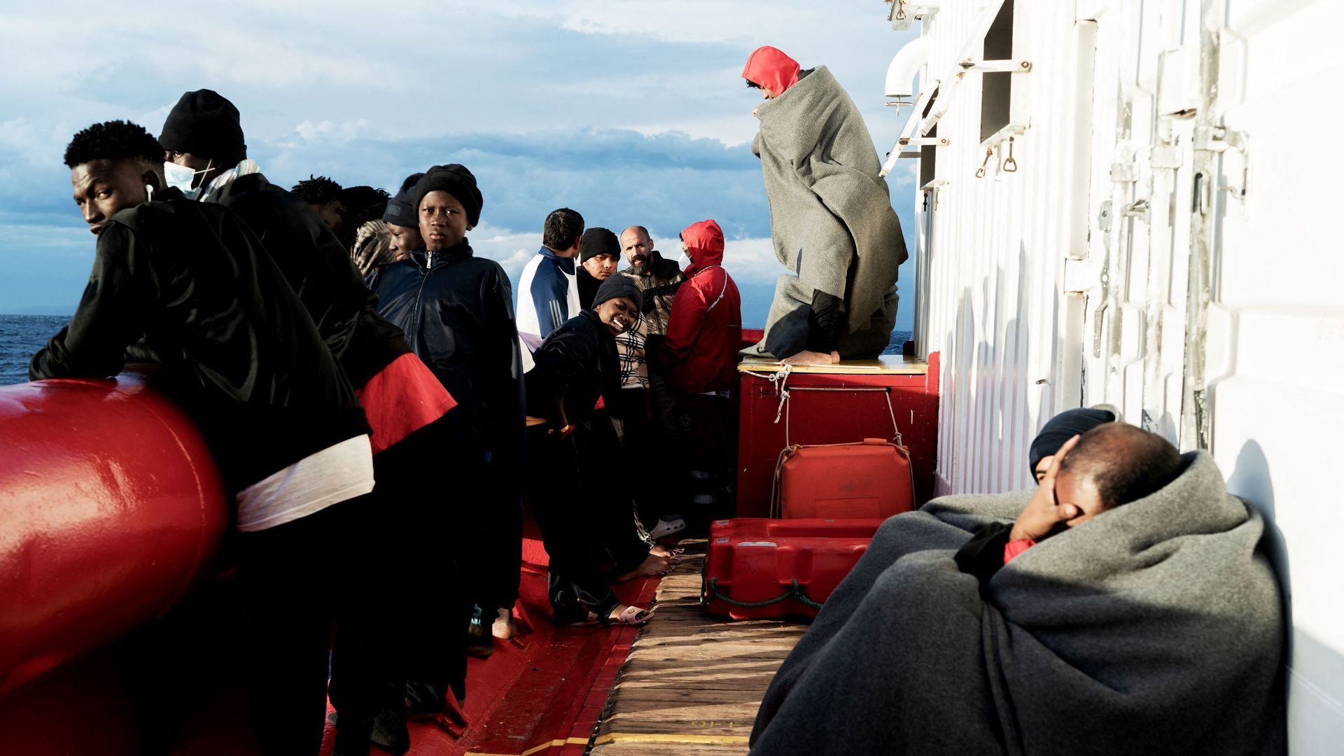 Des migrants regardent et attendent sur le pont du navire de sauvetage "Ocean Viking" de l’organisation maritime-humanitaire européenne "SOS Méditerranée" dans le golfe de Catane en mer Méditerranée dans les eaux internationales, le 6 novembre 2022.