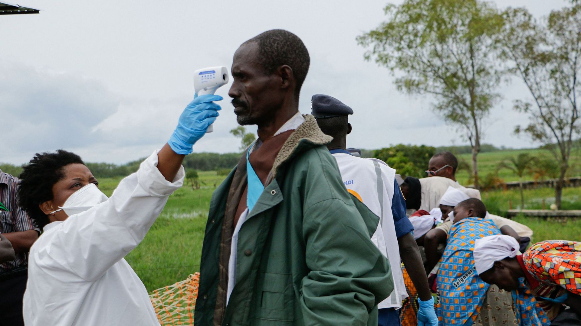 Un membre du personnel médical mesure la température d'un homme à titre préventif contre le coronavirus COVID-19 à son arrivée de rapatriement à Gatumba, à la frontière avec la République démocratique du Congo (RDC), au Burundi, le 18 mars 2020. 