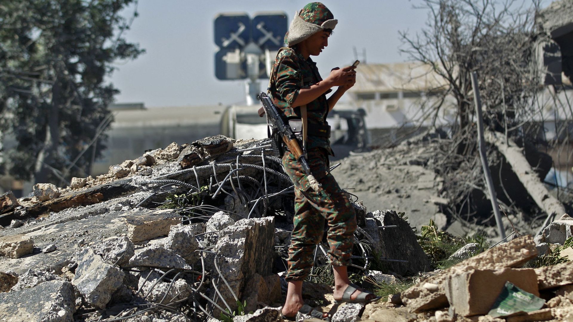 Un soldat loyal aux Houthis au milieu des débris après une frappe visant l'aéroport de Sanaa, le 21 décembre 2021.