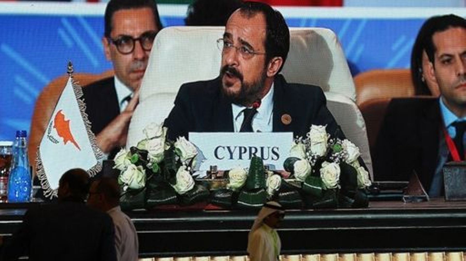 Journalists watch a large screen showing Cyprus' President Nikos Christodoulides addressing the International Peace Summit hosted by the Egyptian president in the New Administrative Capital (NAC), about 45 kilometres east of Cairo, on October 21, 2023, am