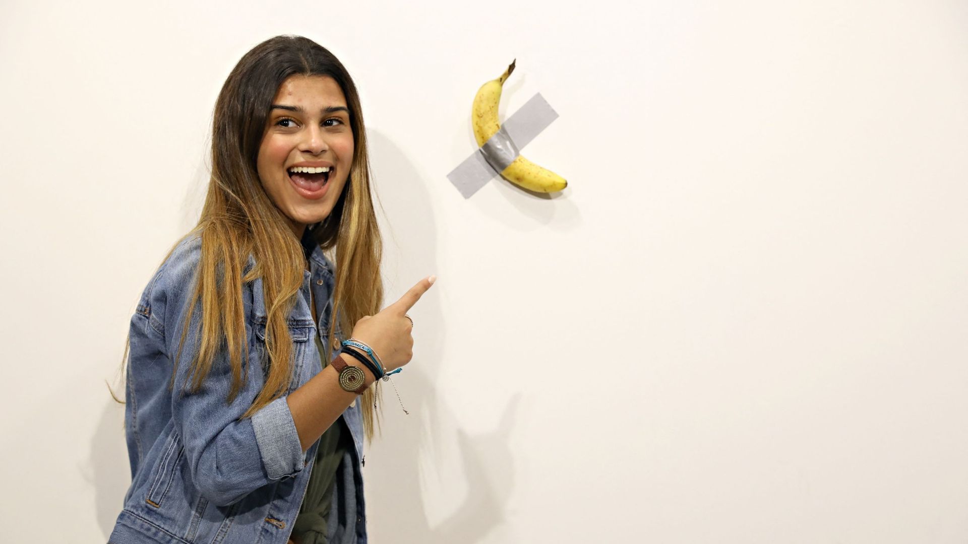 Une visiteuse de la foire Art Basel Miami 2019 pose devant la banane scotchée de Maurizio Cattelan, une oeuvre vendue 120.000 $