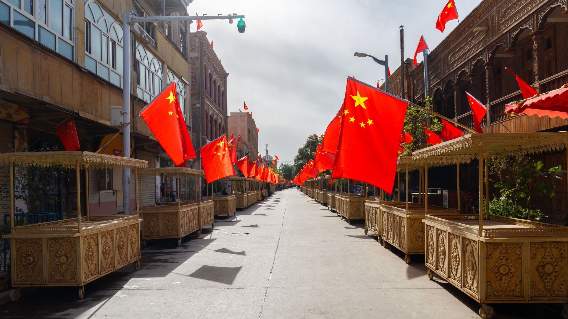 Rue avec des étals de marché dans la vieille ville de Kashgar, avec des drapeaux chinois sur chaque stand, en 2017