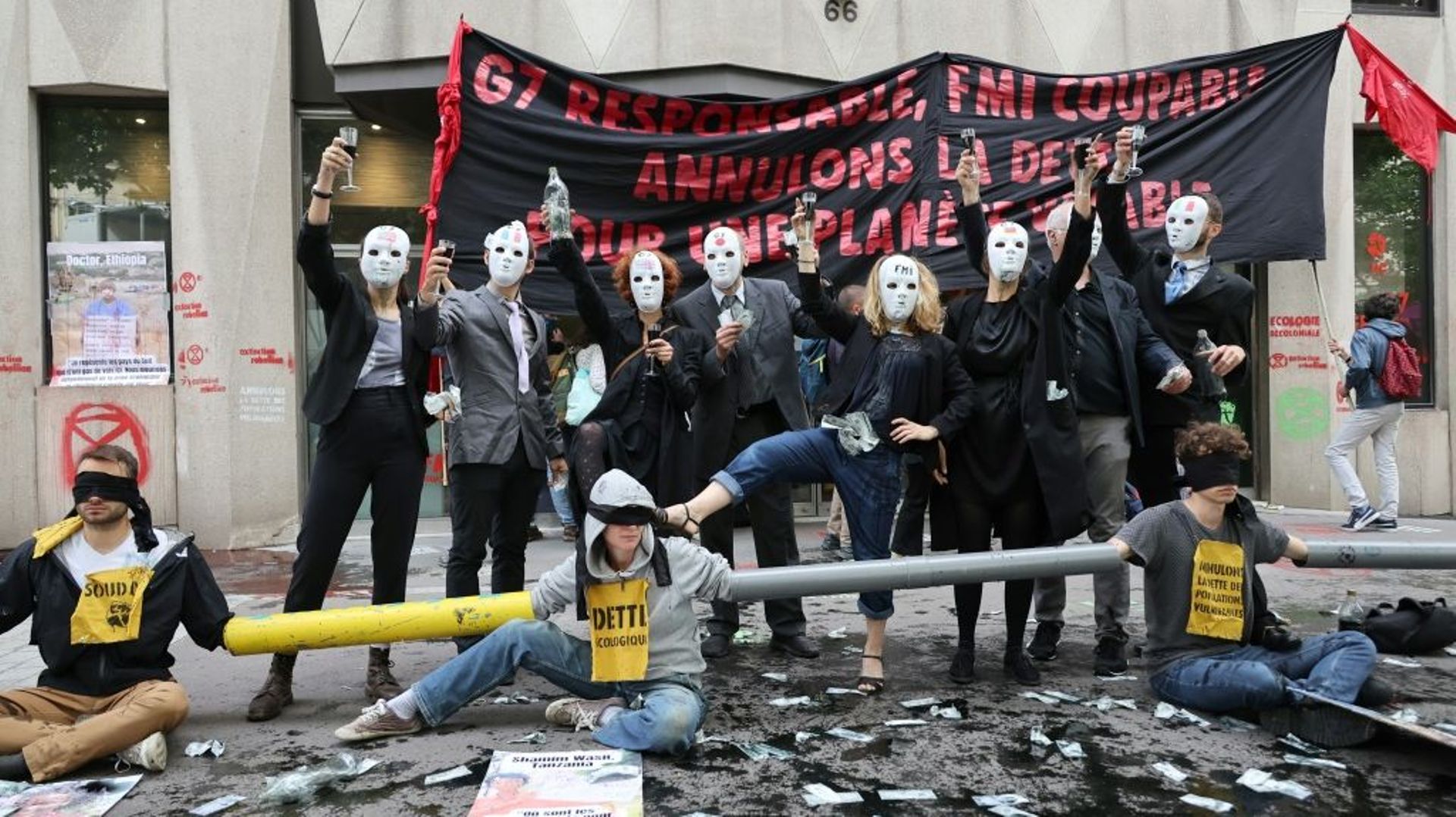 Des militants d'Attac, Extinction Rebellion, de Youth for Climate bloquent l'entrée du bâtiment du FMI pour réclamer l'annulation de la dette des pays du Sud, le 27 juin 2022 à Paris 