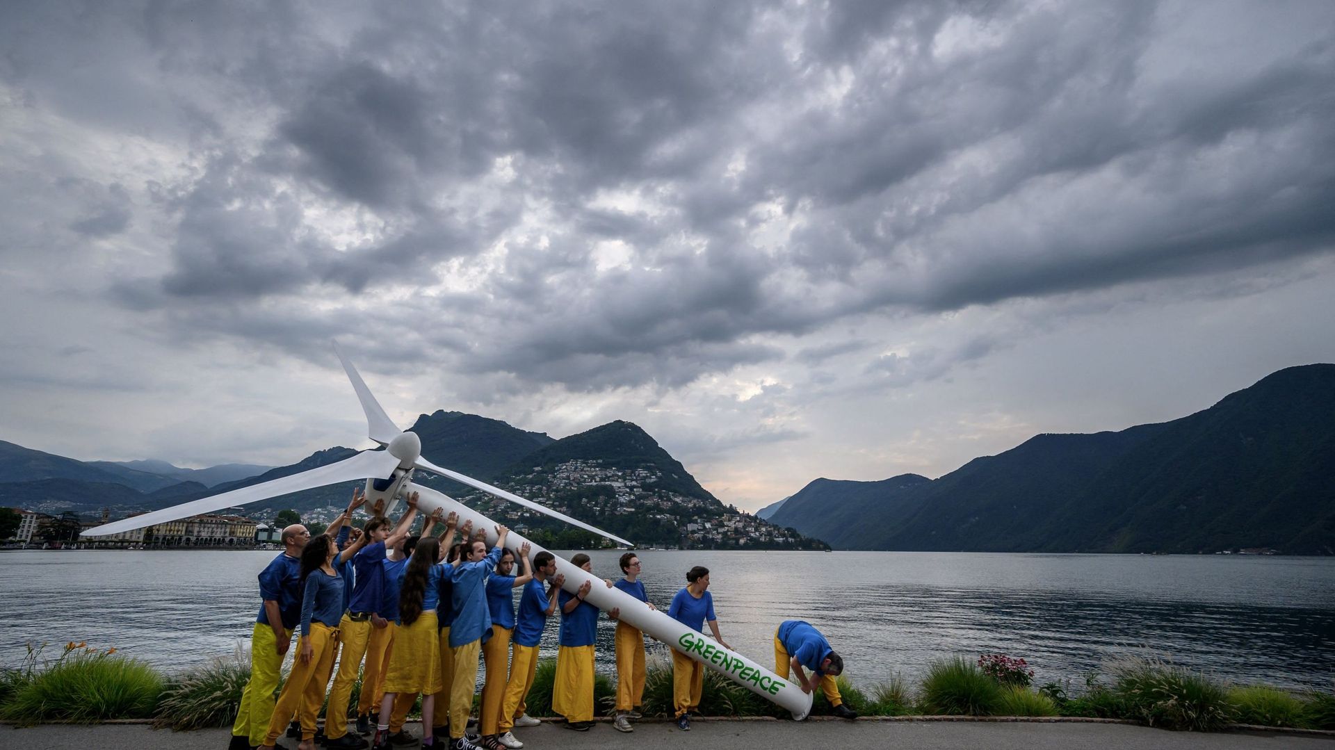 Des militants de Greenpeace lèvent une éolienne factice au bord du lac de Lugano en vue de la conférence sur la relance de l’Ukraine.