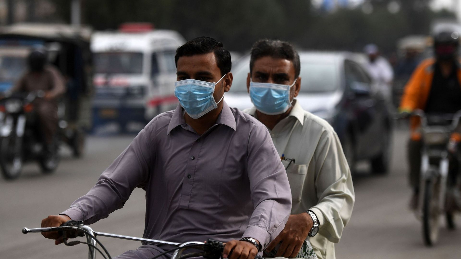 Les banlieusards portent des masques faciaux dans une rue de Karachi le 28 février 2020 alors que le Pakistan a détecté ses deux premiers cas de nouveau coronavirus. Les autorités pakistanaises se sont précipitées le 27 février pour dépister des centaines