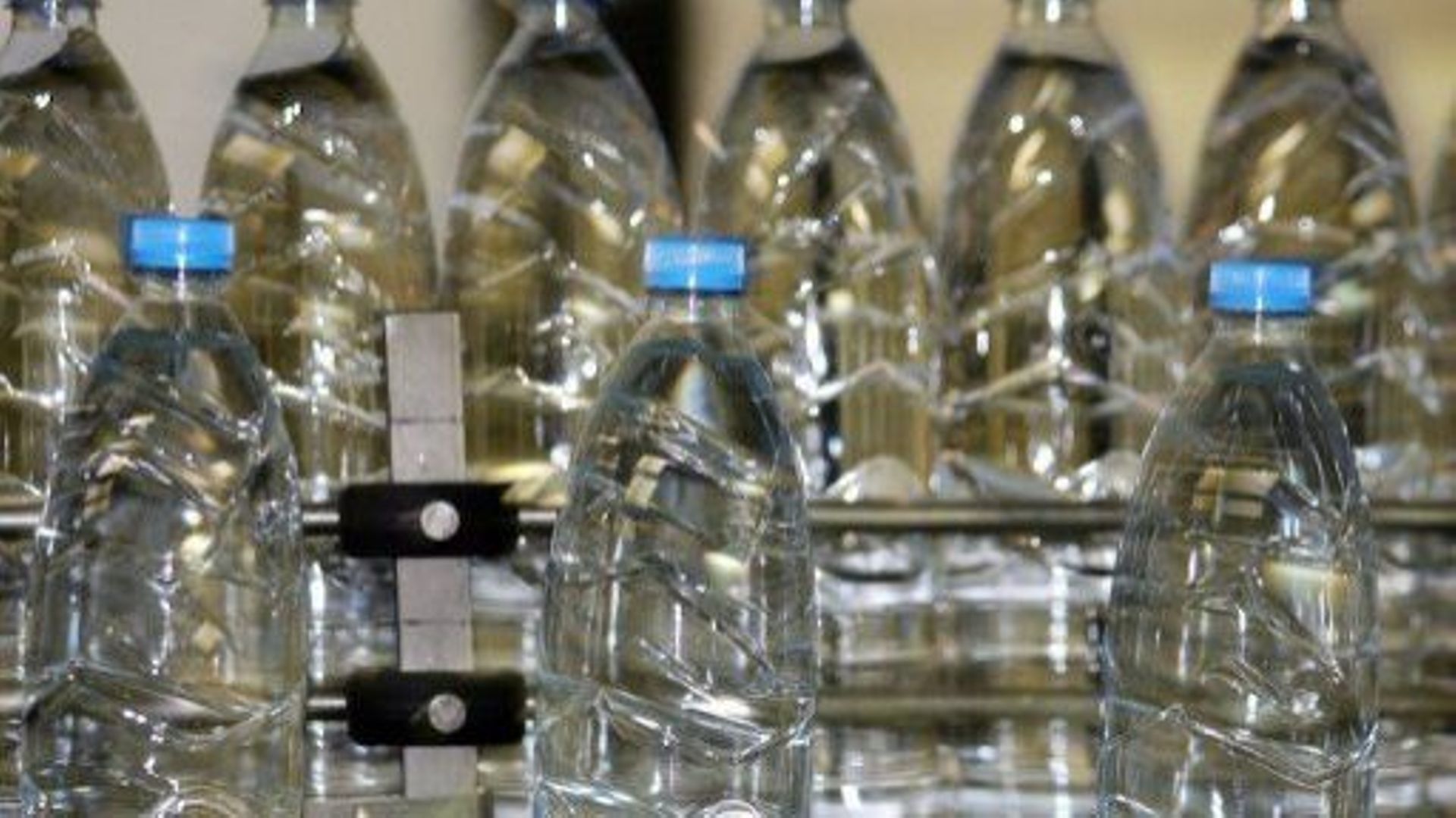 Des bouteilles d'eau défilent sur un tapis roulant dans une usine de production d'eau minérale