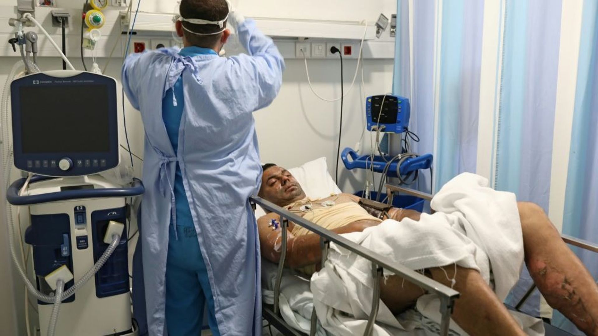 Une soignante s'occupe d'un patient blessé dans l'explosion d'une citerne essence à Tiel, dans une chambre de l'hôpital Geitawi, le 15 août 2021 à Beyrouth