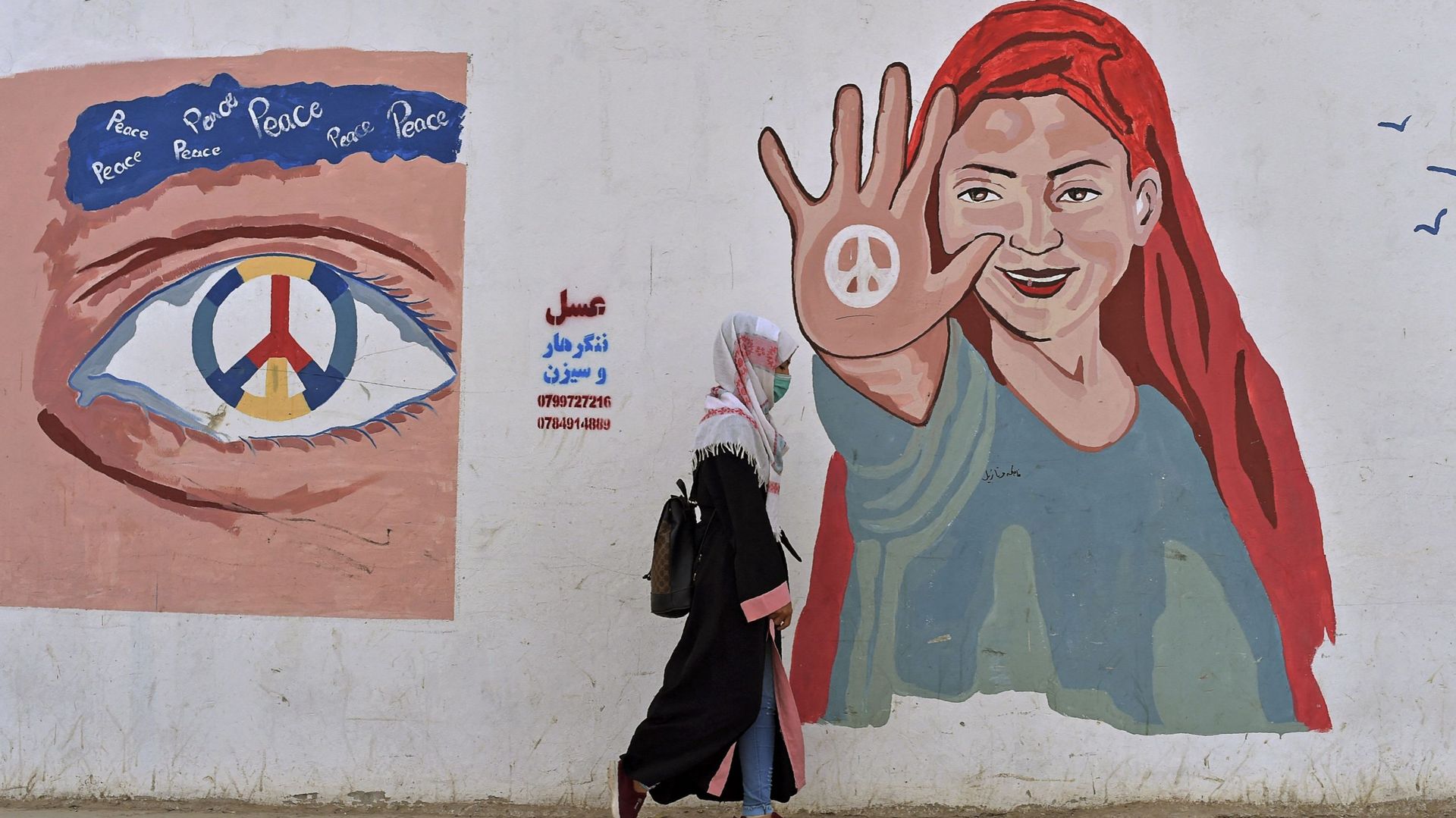 Une femme passe devant une fresque peinte sur le mur le long d’une route à Mazar-i-Sharif en Afganistan, ce 31 octobre 2021. Photo d’illustration