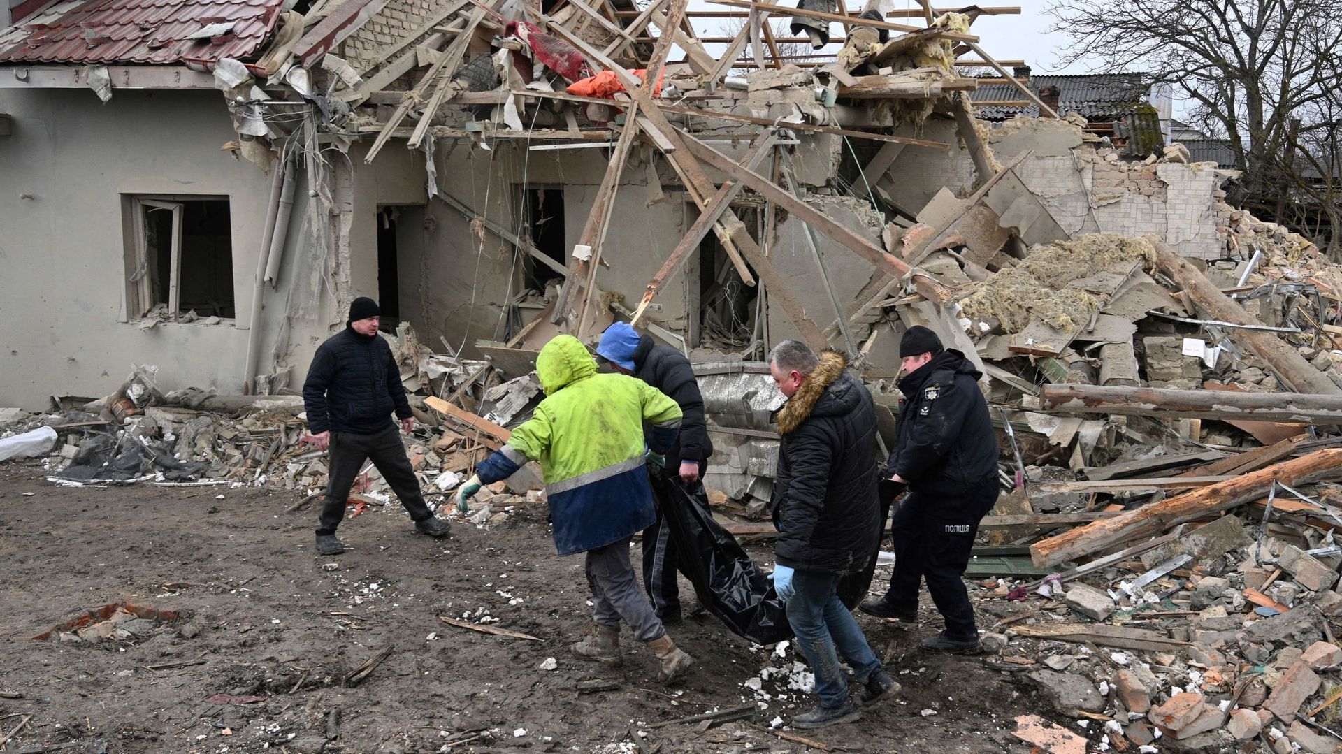 Des experts de la police et des habitants de la région transportent un corps non identifié à la suite d'une attaque russe dans le village de Velyka Vilshanytsia, à une cinquantaine de kilomètres de Lviv, le 9 mars 2023.