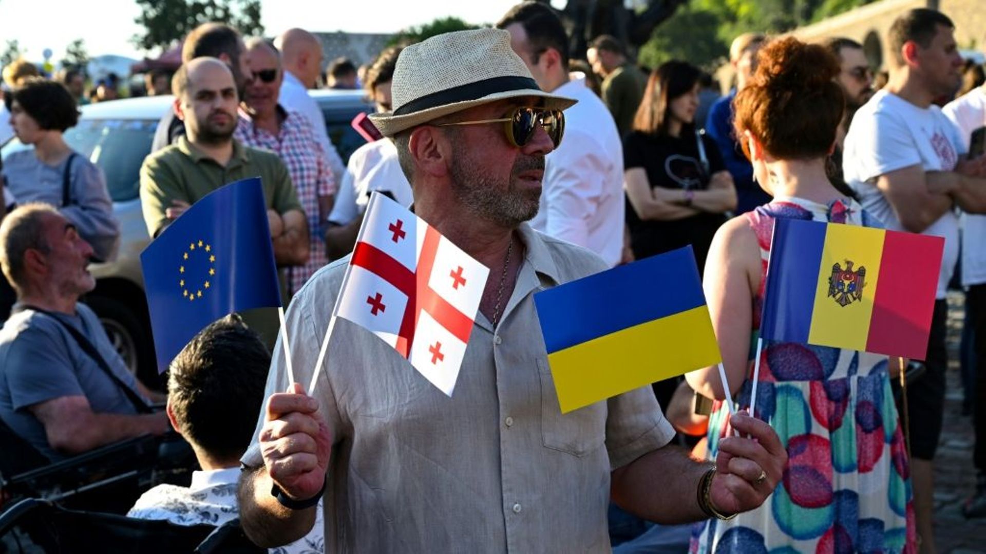 Un homme brandit des drapeaux de l’Union européenne et de l’Ukraine, entre autres, en Géorgie, à Tbilissi le 16 juin 2022
