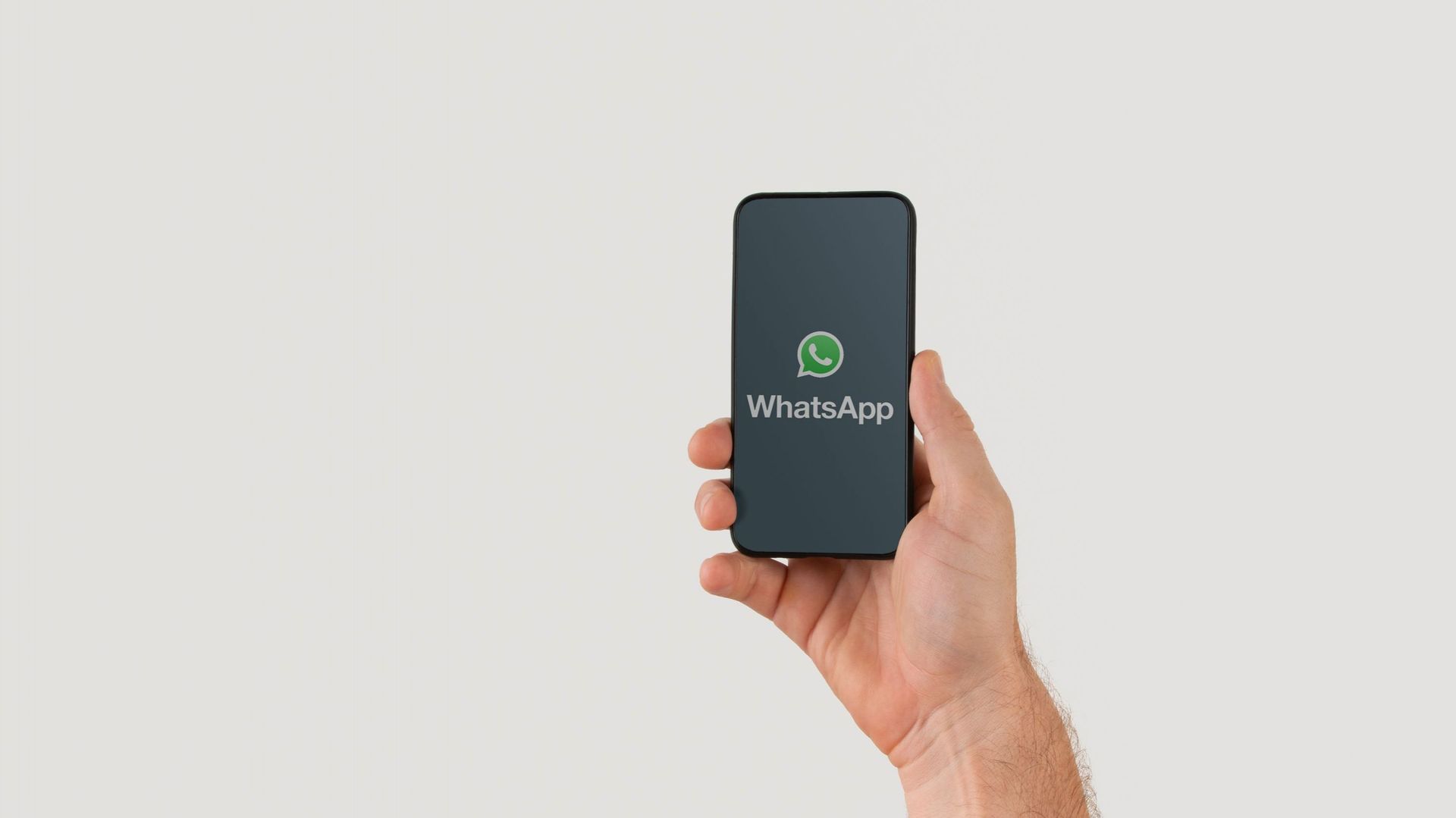 Hand holding smart phone with popular online text / call application &#34 ; WhatsApp&#34 ; logo on screen. Illustrative editorial image with copy space for text.
