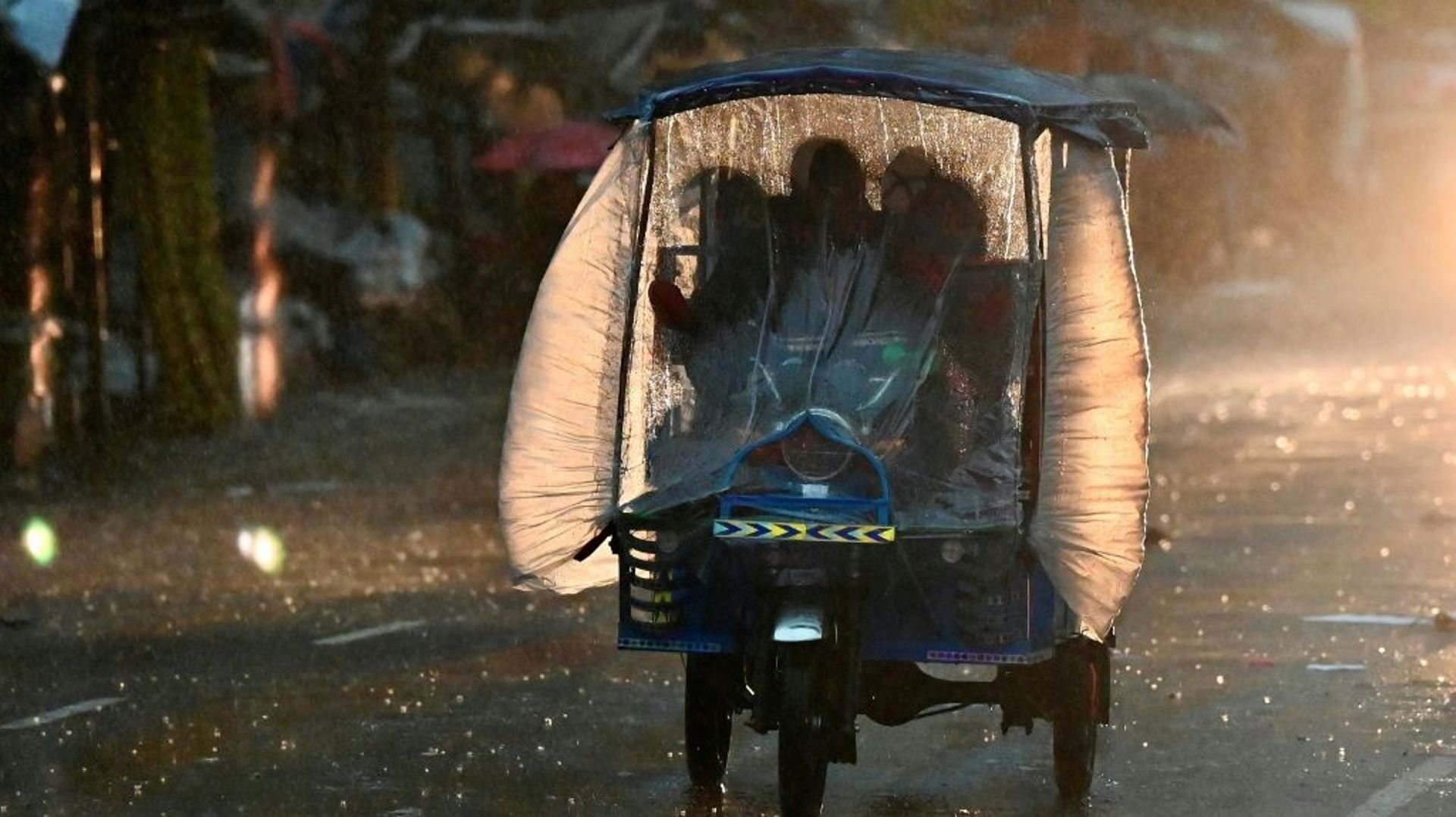 Des personnes en rickshaw sous une pluie violente, le 24 octobre 2022 à Faridpur, au Bangladesh.