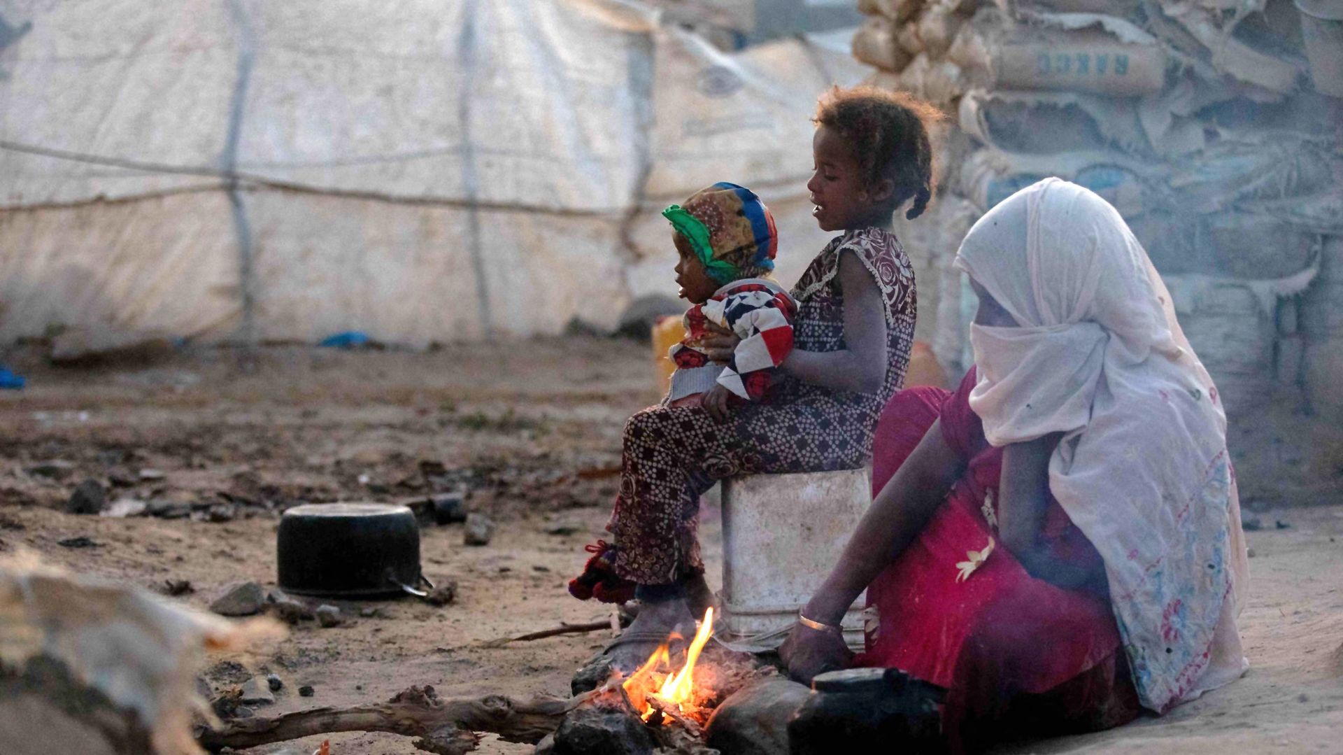 Des personnes se réchauffent près d'un feu dans un camp pour personnes déplacées à la périphérie de la troisième ville du Yémen, Taez, le 11 janvier 2022.
