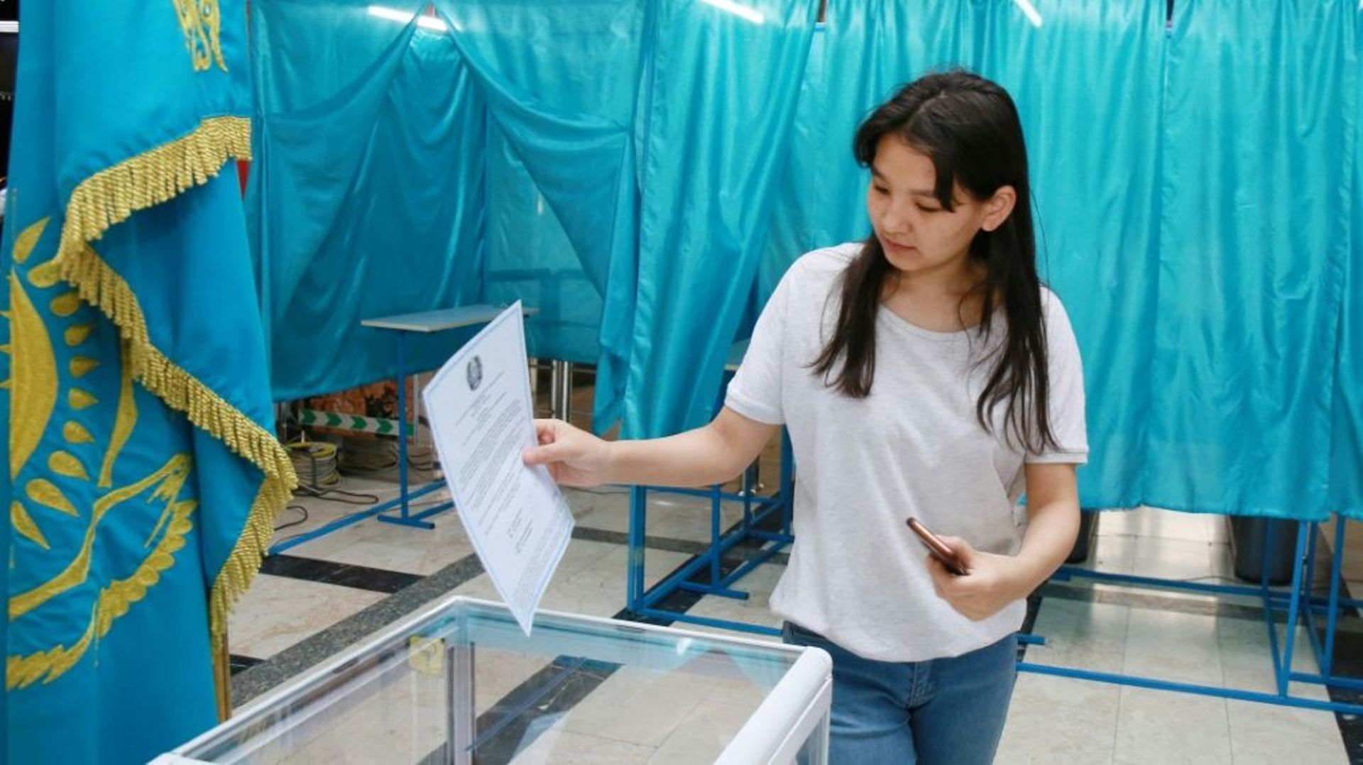 Une femme glisse son bulletin dans une urne d'un bureau de vote à Almaty, le 5 juin 2022