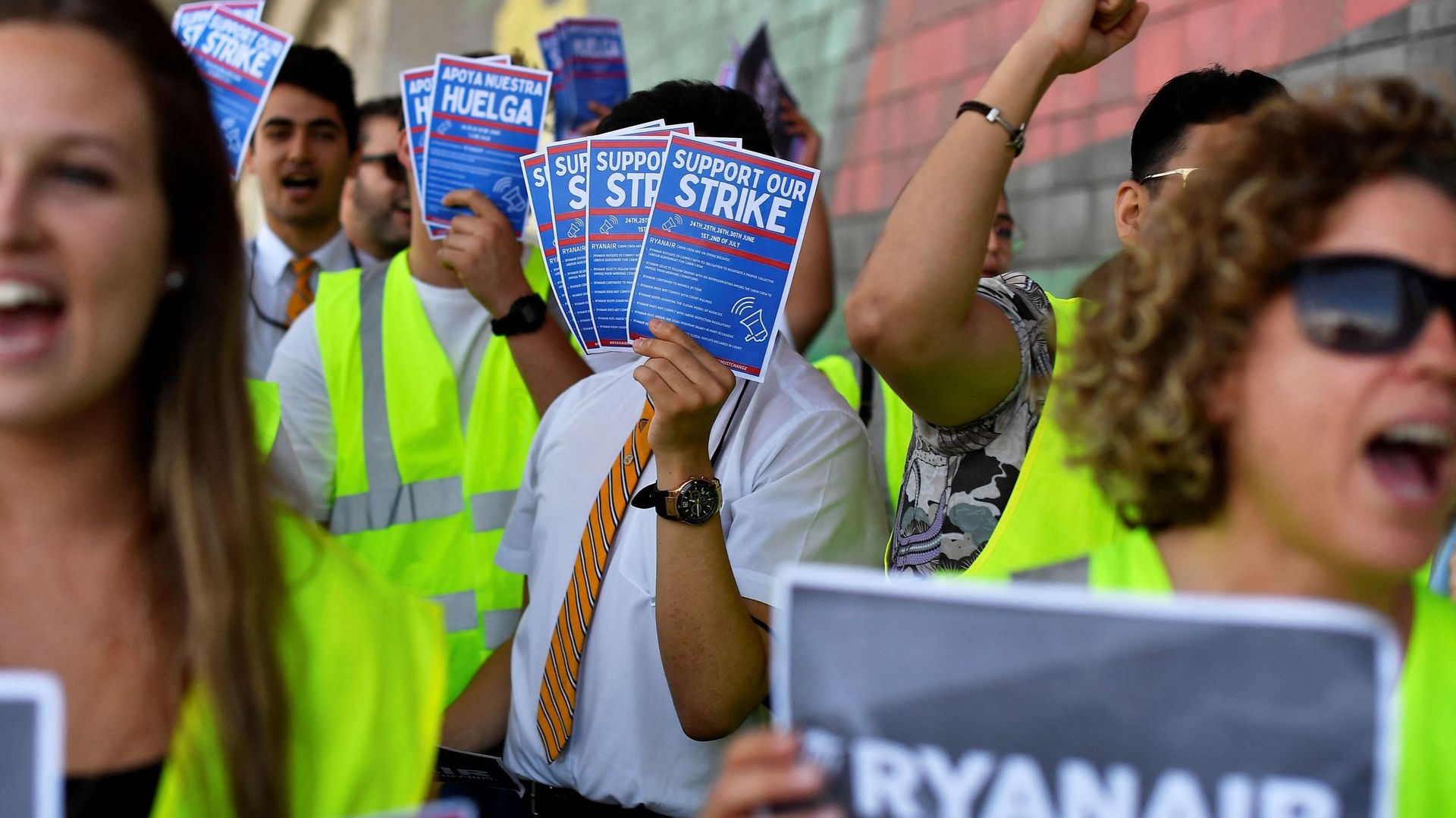 Des employés de Ryanair tiennent des tracts sur lesquels on peut lire "Soutenez notre grève", alors qu’ils manifestent au Terminal 2 de l’aéroport El Prat à Barcelone, le 1er juillet 2022.