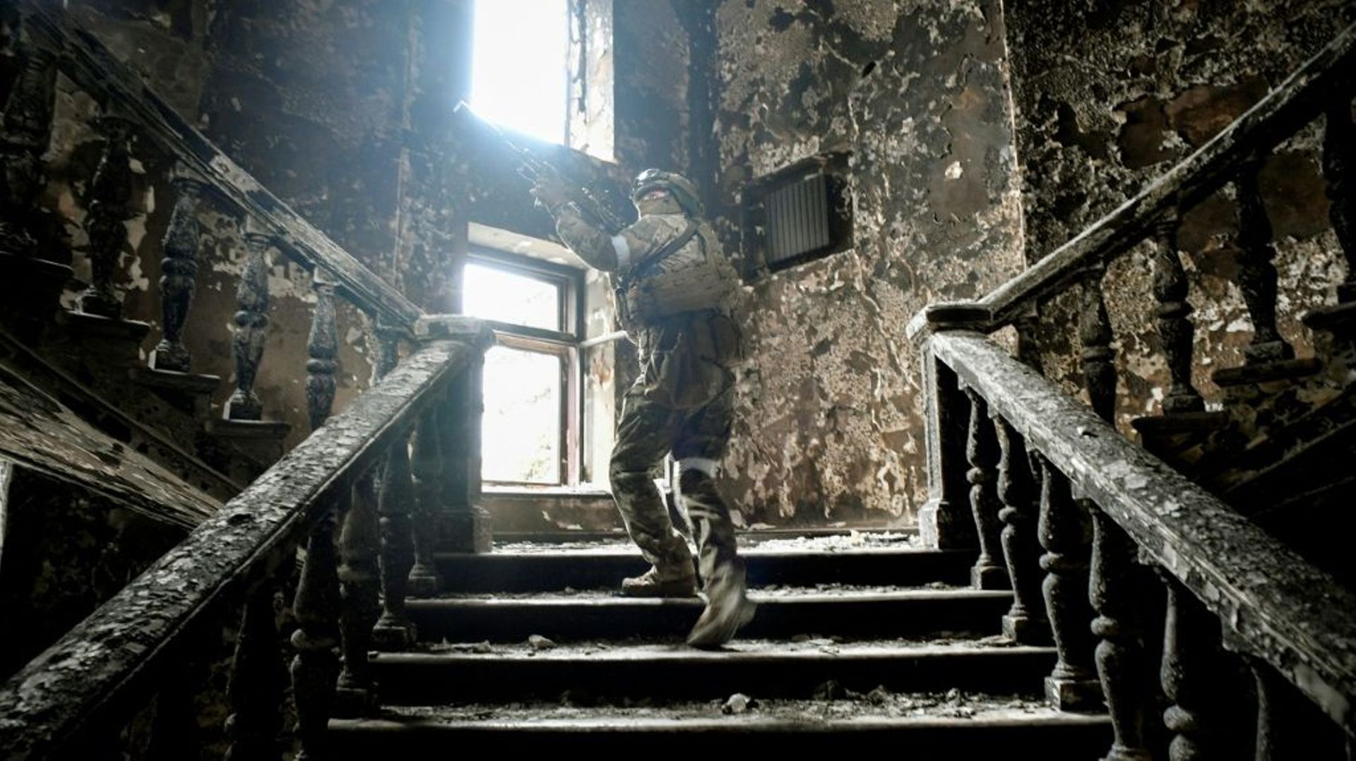Un soldat russe monte les marches du théâtre détruit de Marioupol, le 12 avril 2022