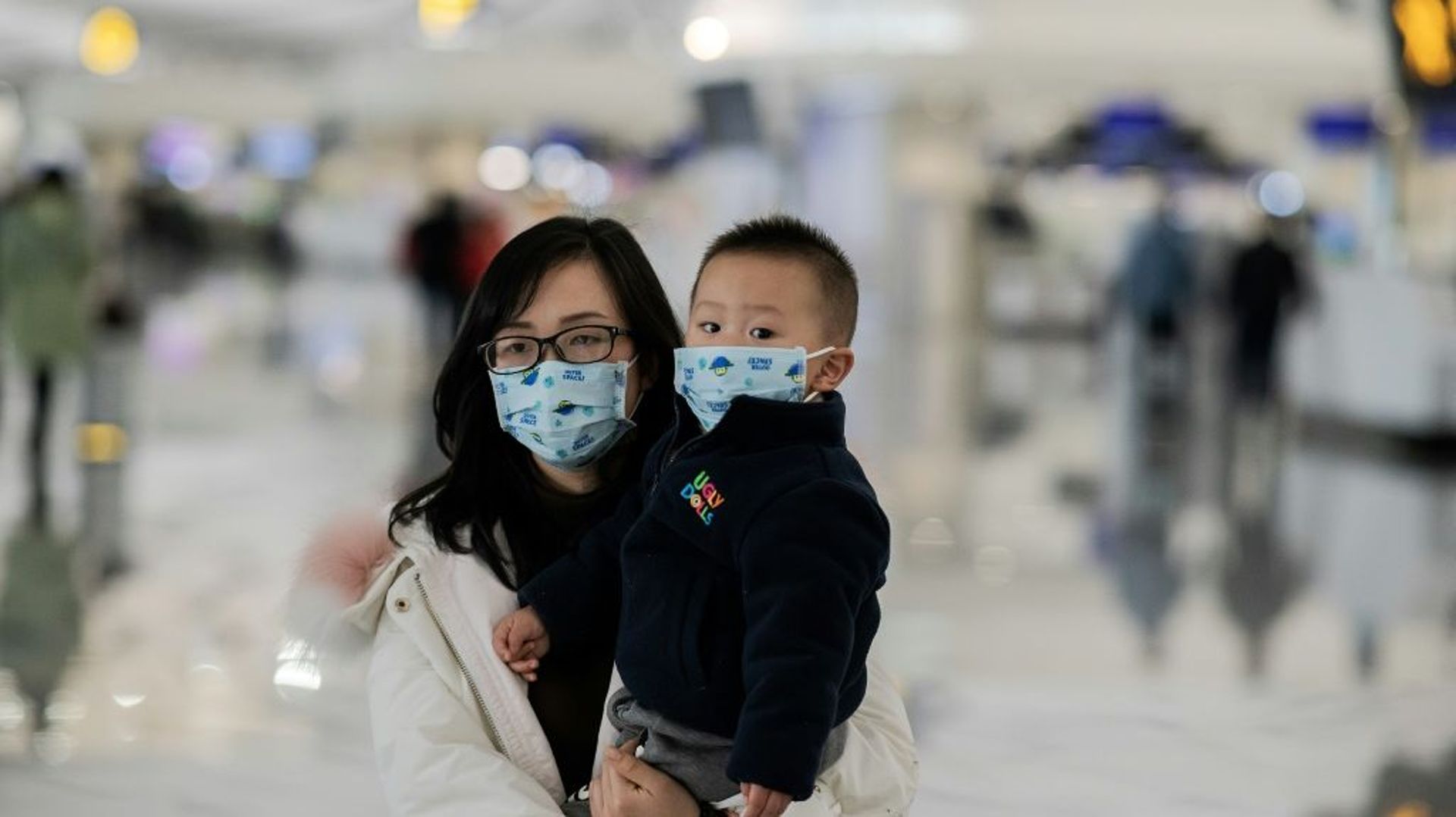 Une femme et un enfant portent un masque de protection à l'aéroport international Daxin de Pékin le 21 janvier 2020