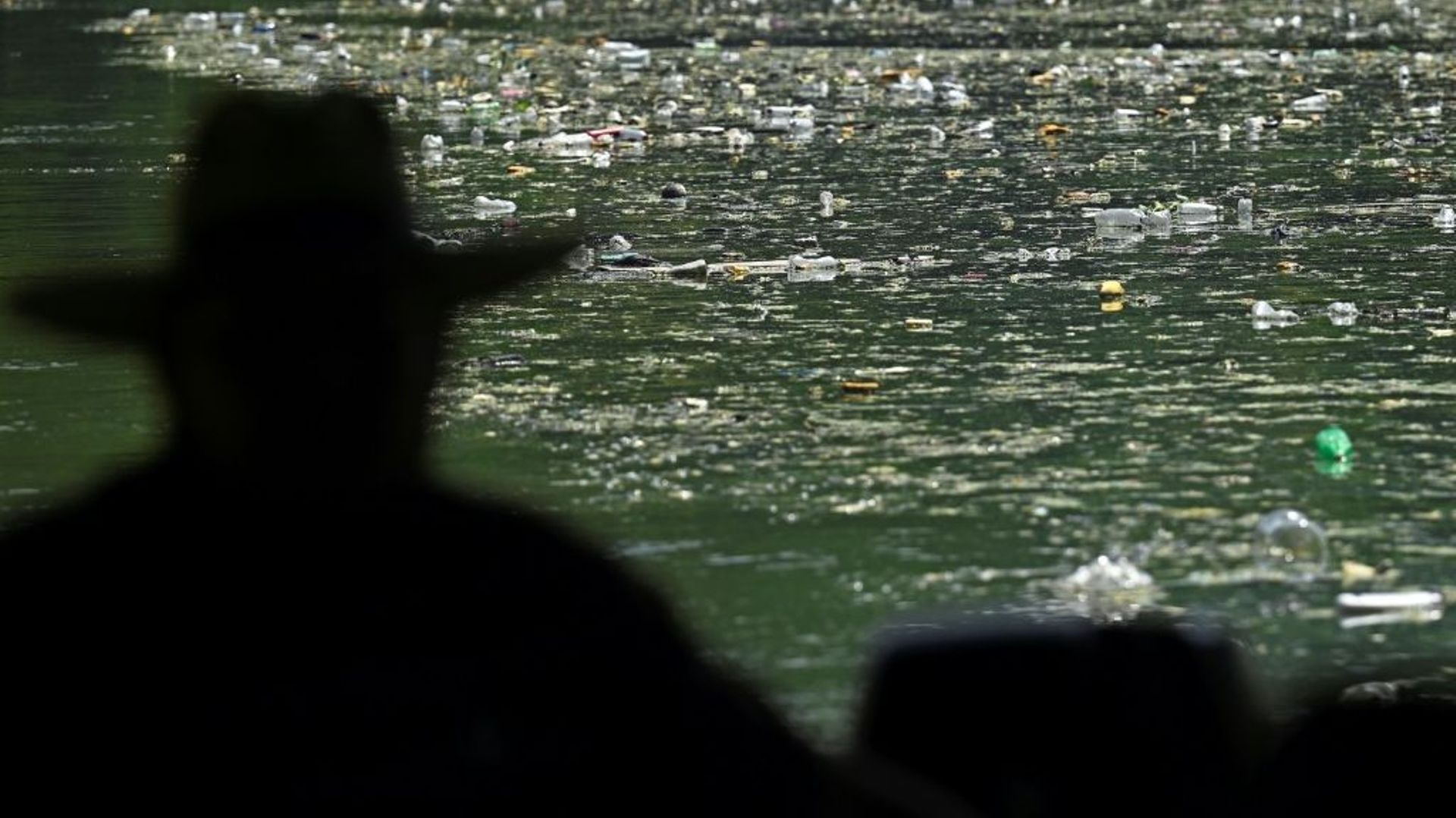 Un pêcheur regarde les déchets qui polluent le réservoir de Cerron Grande, à Potonico, le 9 septembre 2022 au Salvador