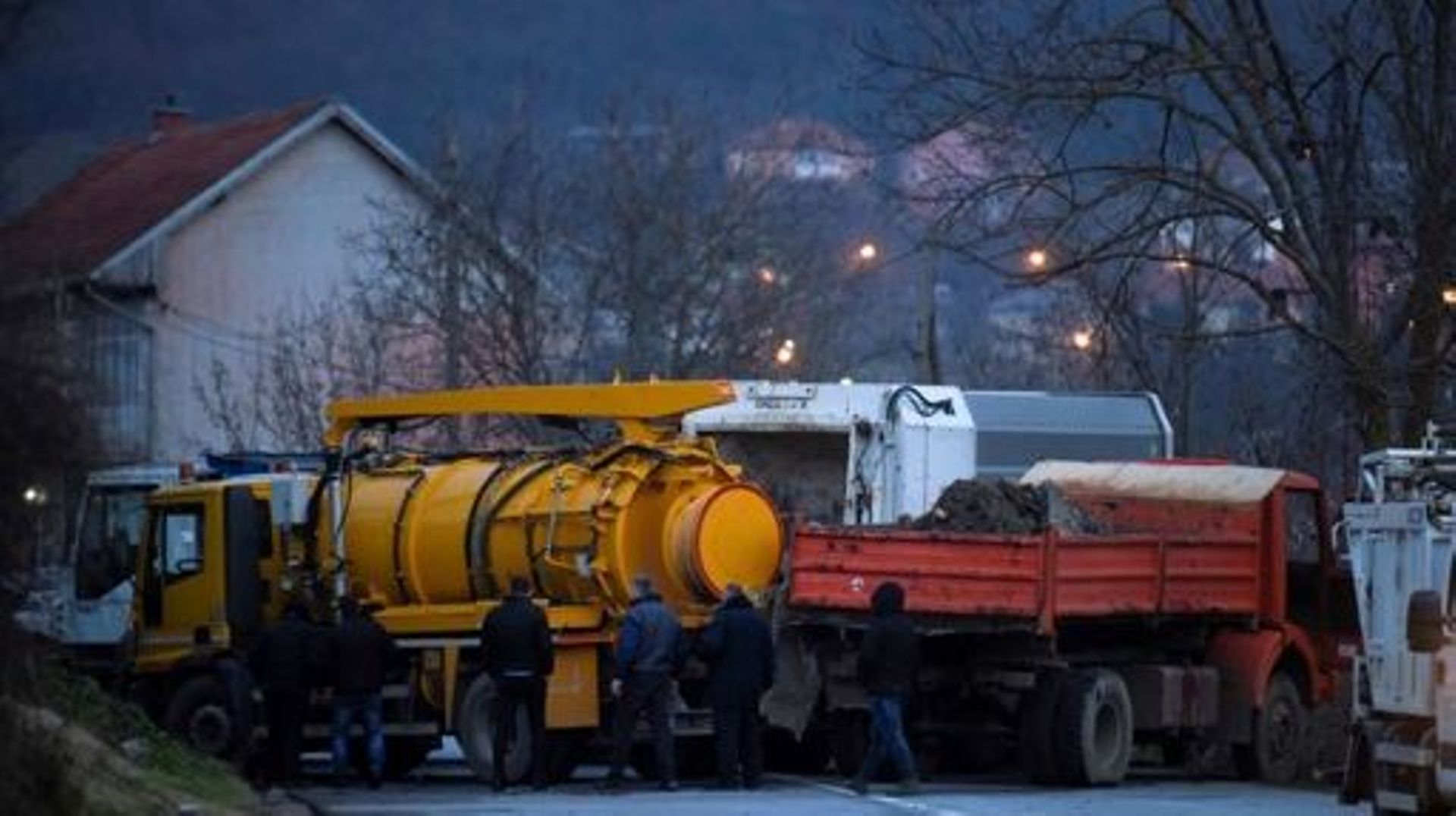 Des passants enlèvent des camions d’une barricade routière érigée par des Serbes de souche dans le village de Rudare, près de la ville de Zvecan, le 29 décembre 2022.