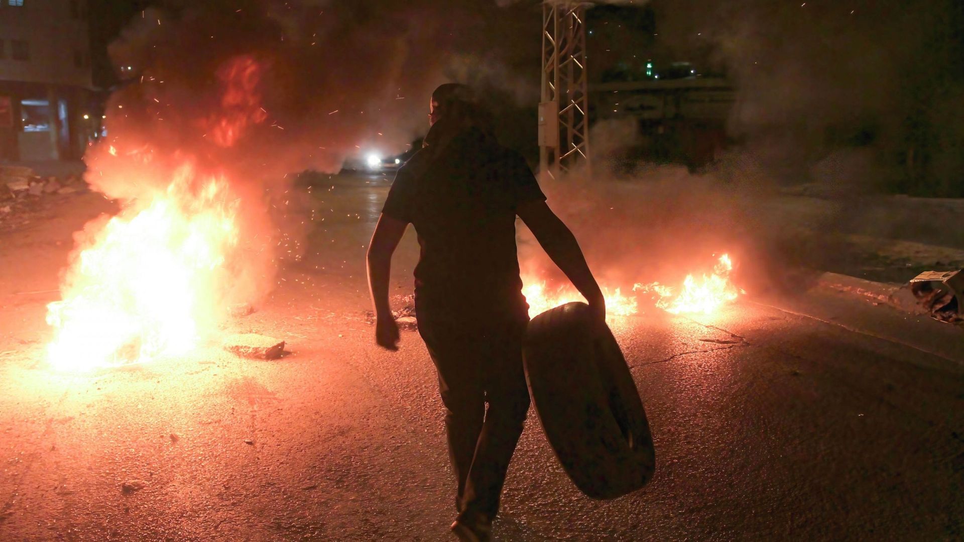 Un Palestinien brûle des pneus sur la route menant au tombeau de Joseph devant les colons juifs lors d'une manifestation contre leur pèlerinage. 