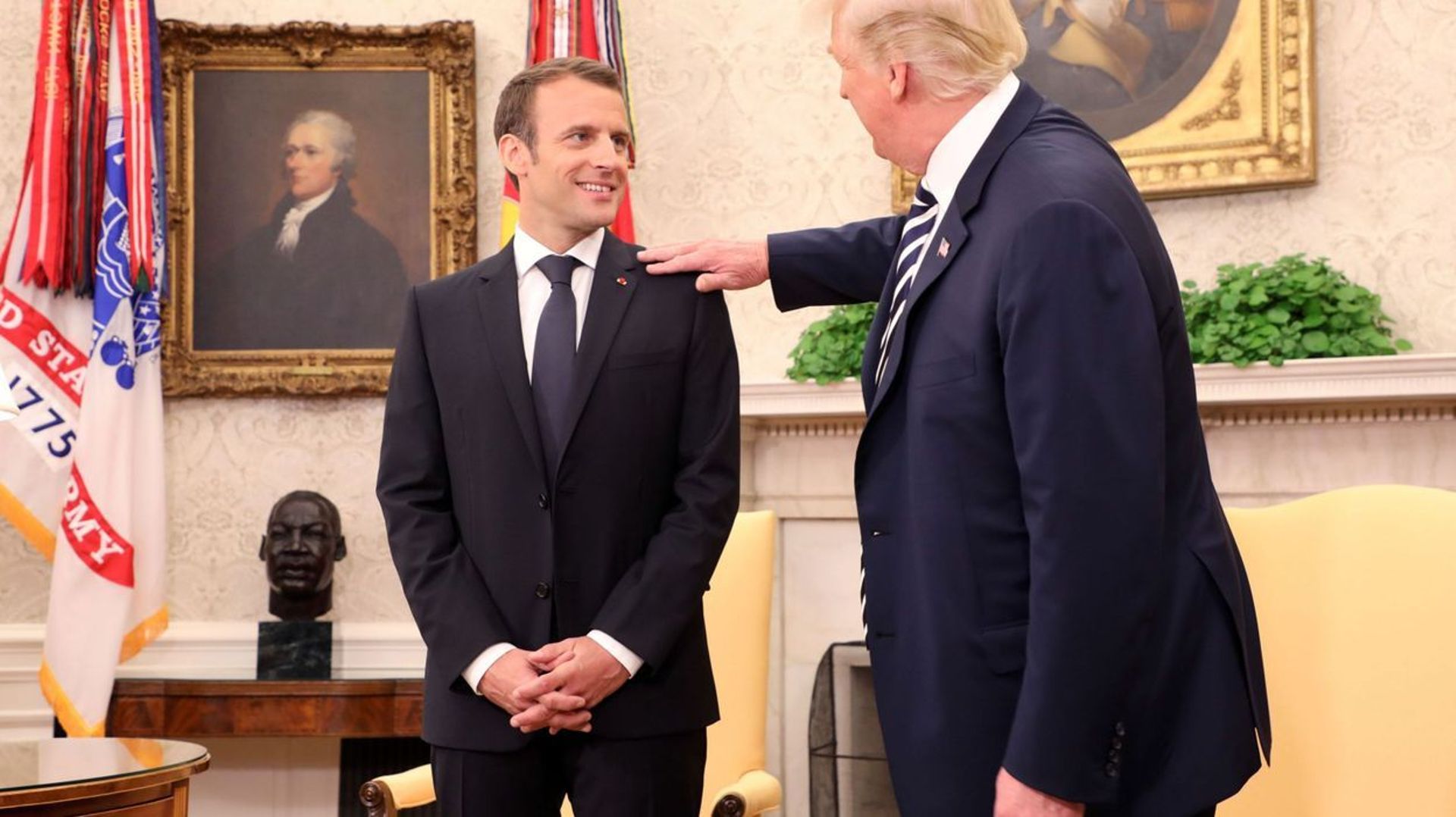 Dans le bureau ovale, Donald Trump époussette l'épaule d'Emmanuel Macron.