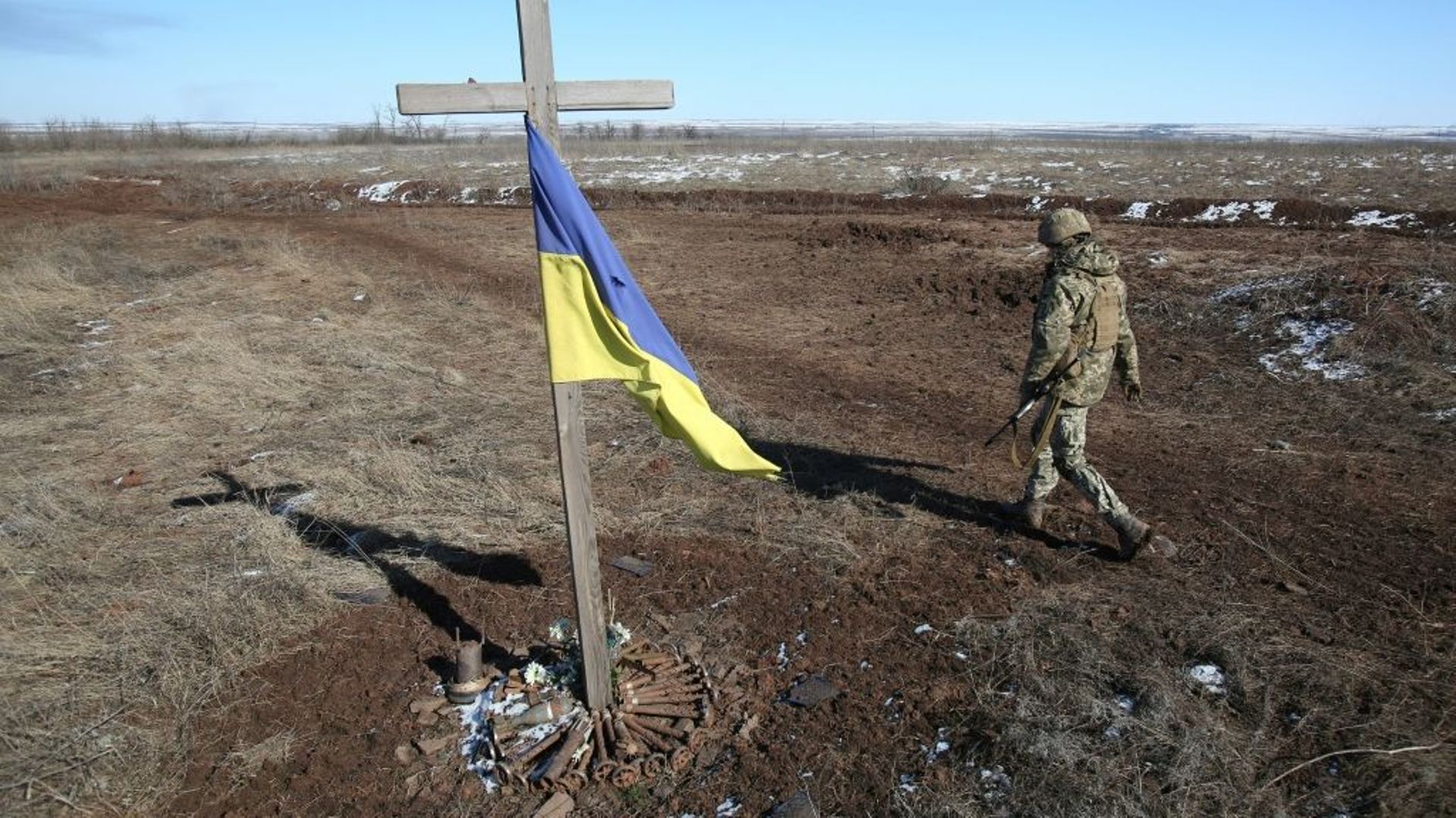 Un soldat ukrainien passe à côté d’un mémorial de fortune à Svetlodarsk, près de Donetsk, en Ukraine, le 12 mars 2022