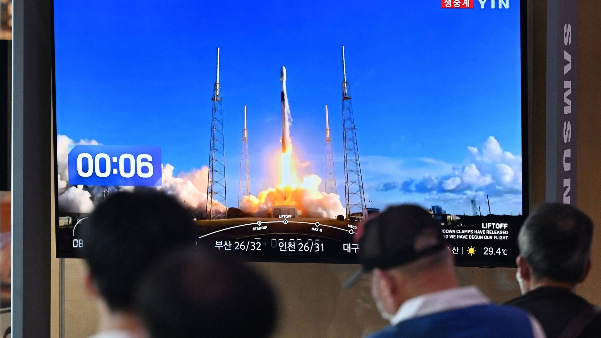 Des personnes regardent un écran de télévision montrant des images en direct du lancement d'une fusée Falcon 9 de SpaceX avec le premier orbiteur lunaire sud-coréen Danuri à bord depuis Cap Canaveral en Floride, dans une gare de Séoul, le 5 août 2022.