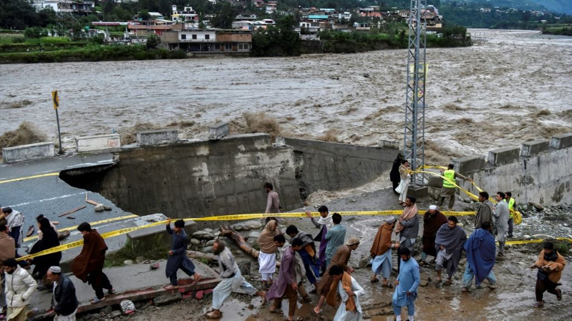 Des personnes se rassemblent devant une route endommagée par inondations consécutives aux fortes pluies de mousson dans la vallée de Swat, dans le nord du Pakistan, le 27 août 2022…