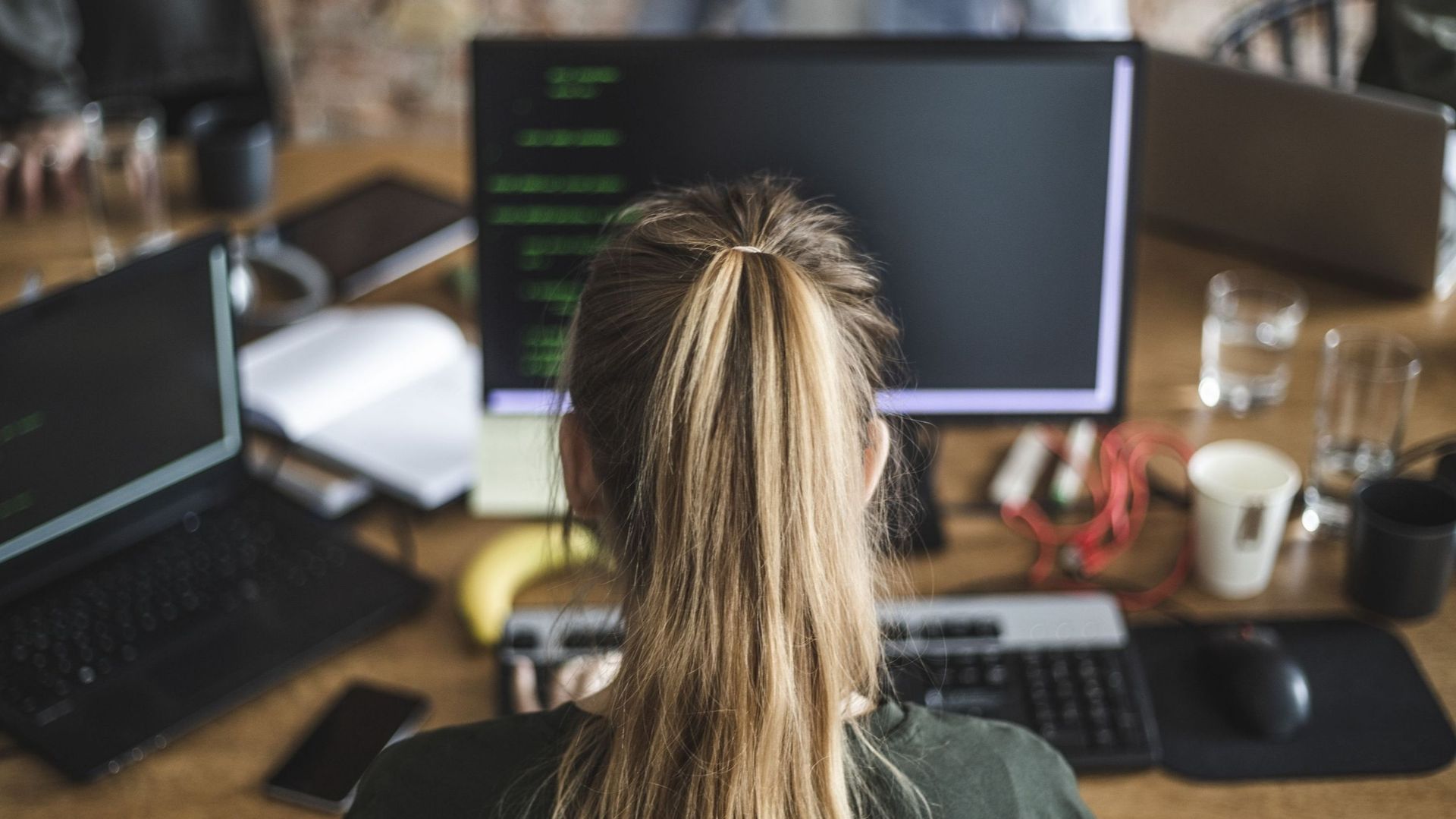 Blond female programmer coding over computer in startup company