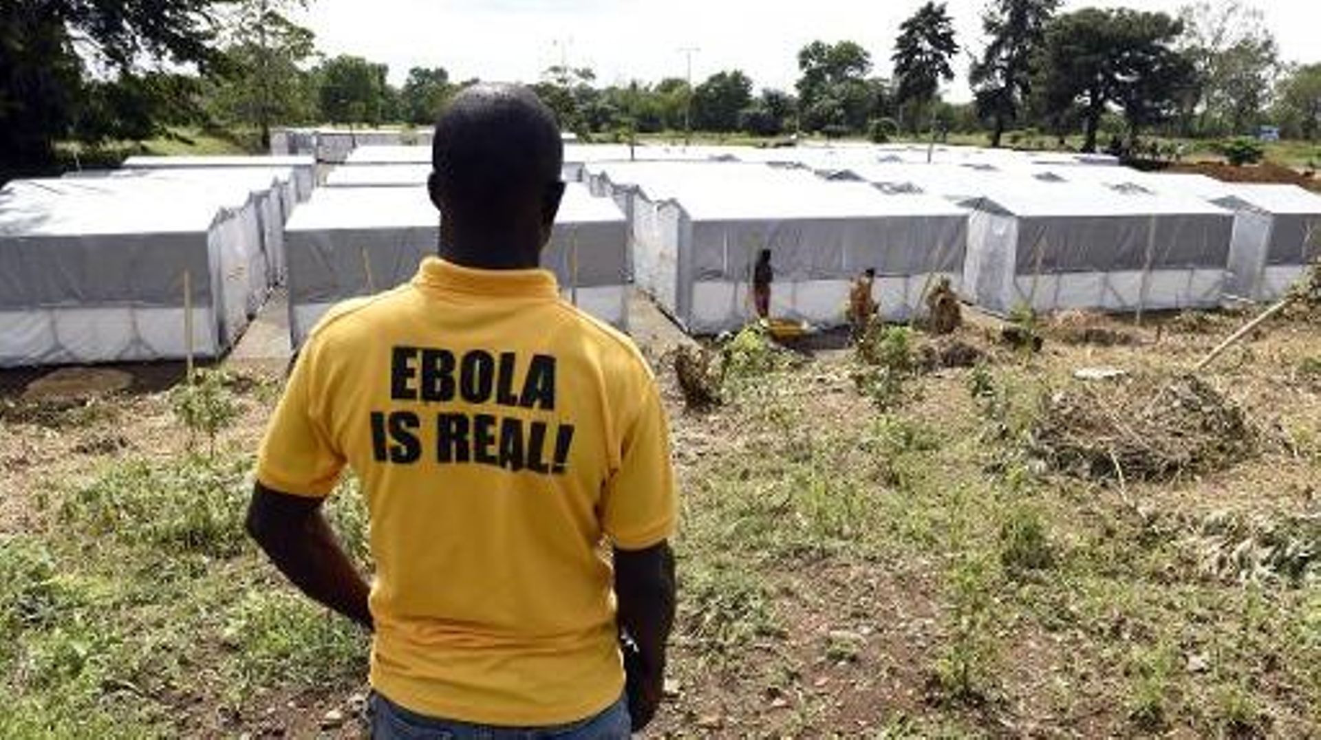 Un homme portant un T-shirt "Ebola est réel" regarde le nouveau centre de traitement des malades atteints du virus Ebola à Monrovia, le 28 septembre 2014
