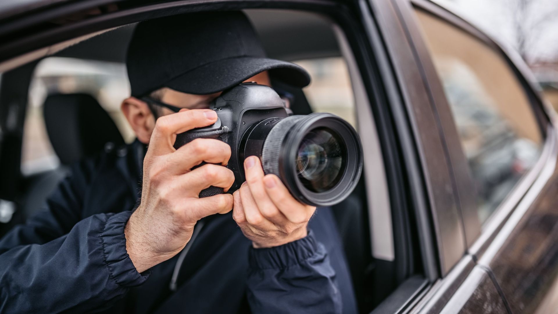 Détective privé prend des photographies depuis une voiture.