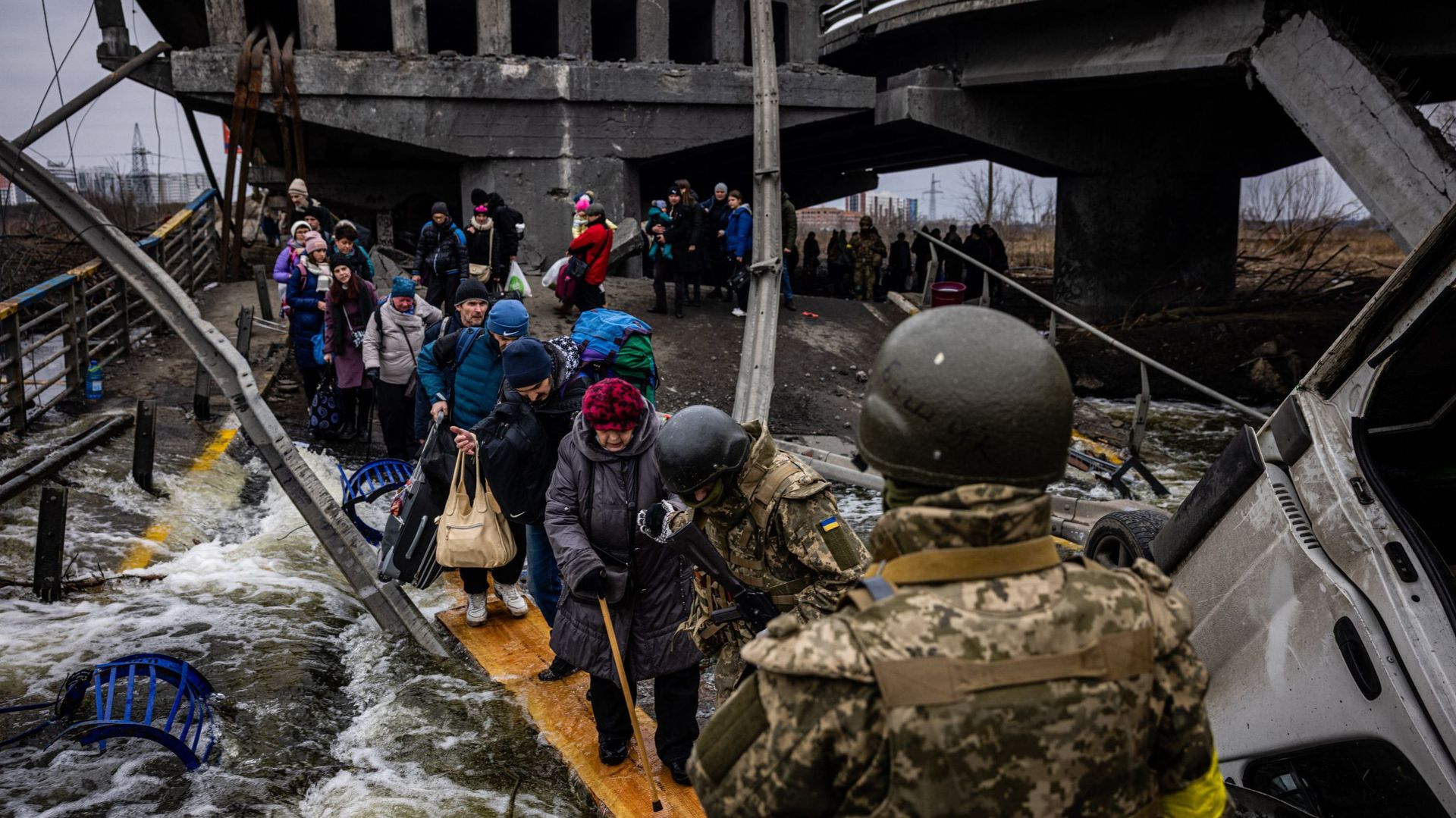 Des personnes évacuées traversent un pont détruit alors qu’elles fuient la ville d’Irpin, au nord-ouest de Kiev, le 7 mars 2022.