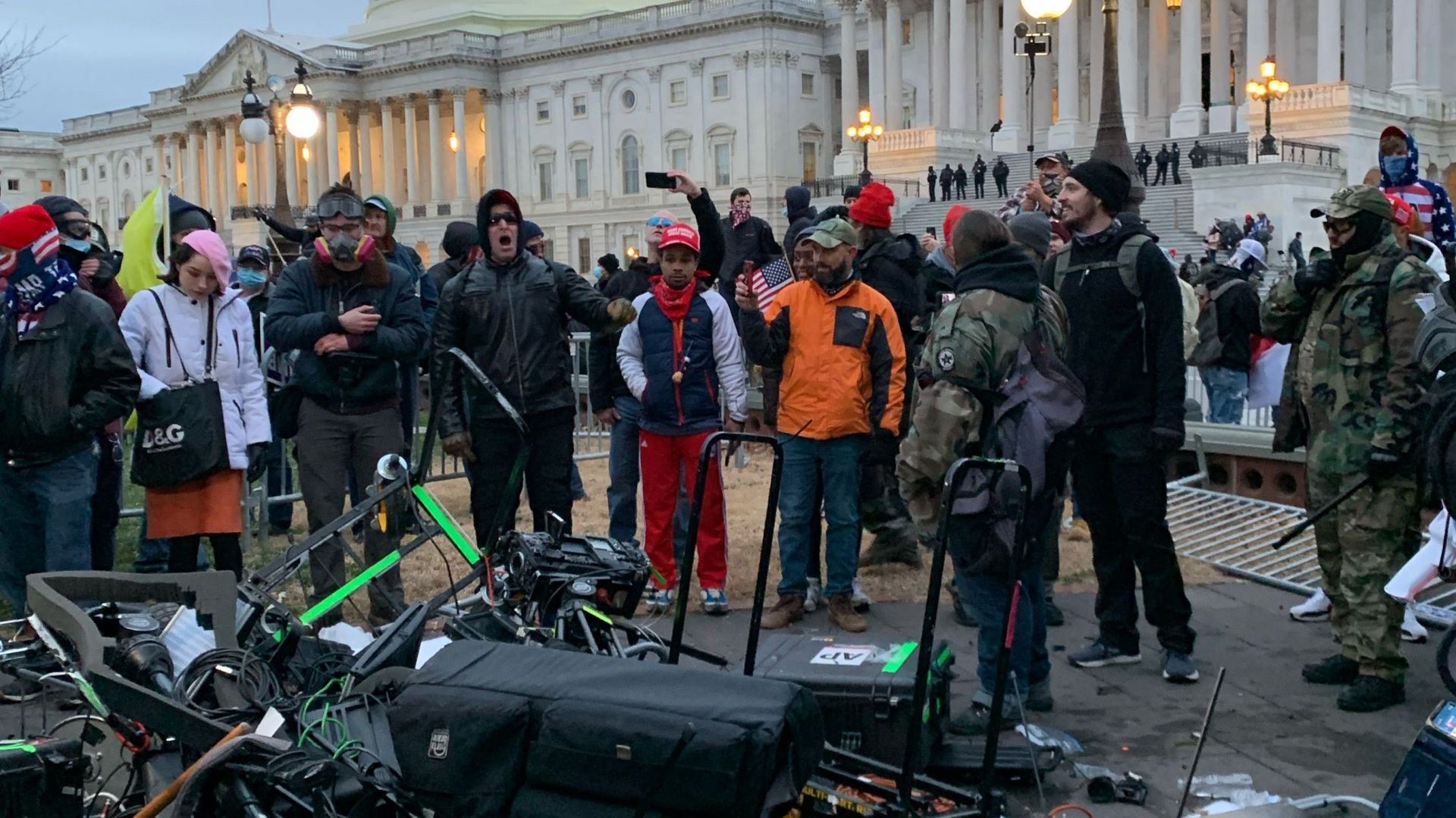 Des personnes se tiennent autour de l'équipement d'Associated Press détruit par les partisans de Trump devant le Capitole américain à Washington DC le 6 janvier 2021.