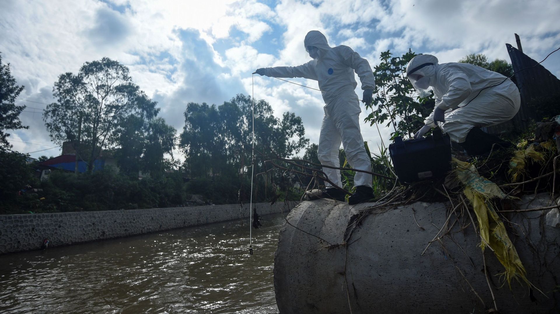 Des chercheurs font des prélèvements dans un égout sur la rivière Manohar près de Katmandou le 7 août 2020. 