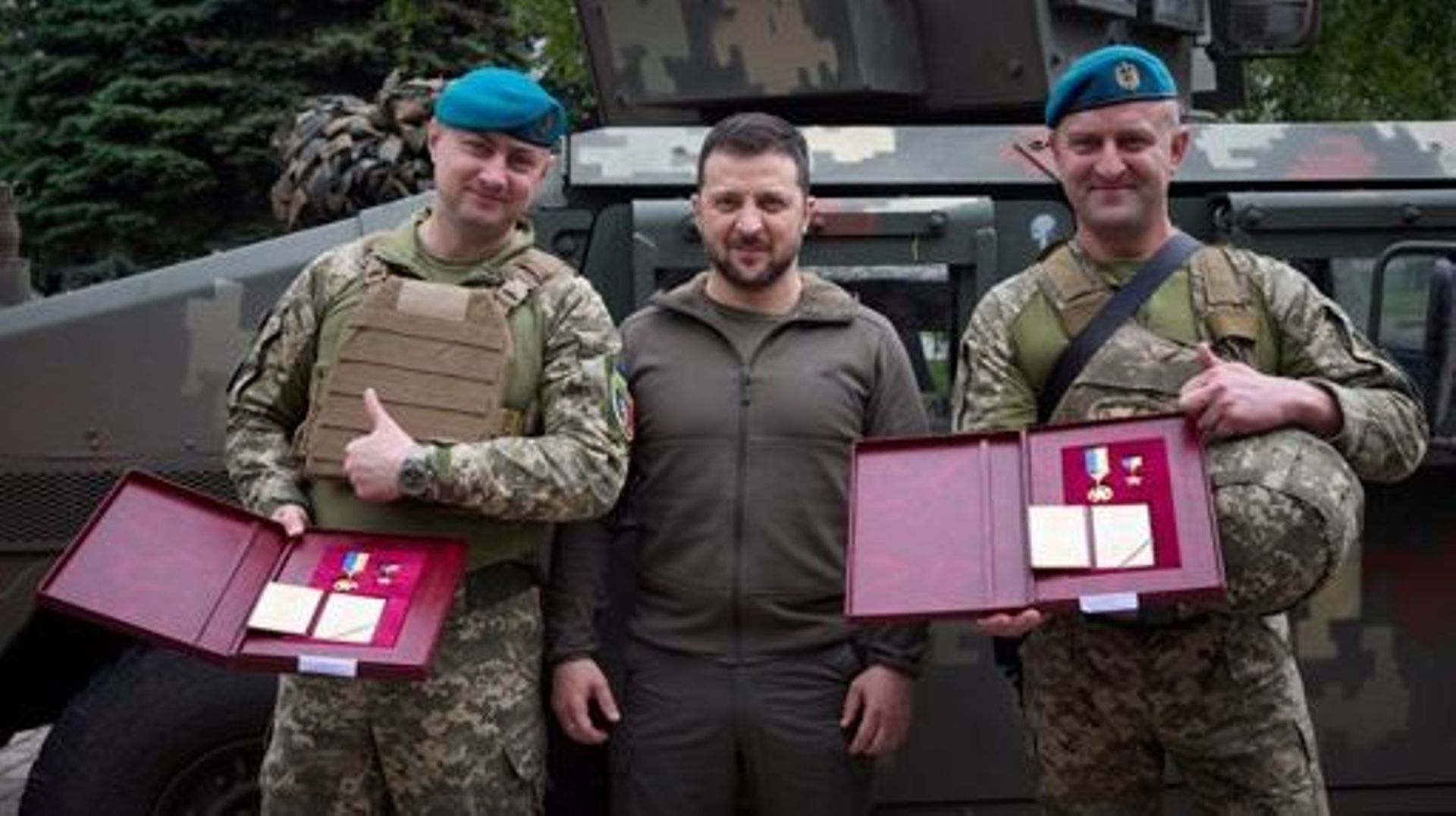 This handout photograph taken and released by Ukrainian Presidential press-service on May 23, 2023 shows President of Ukraine Volodymyr Zelensky (C) posing for a photograph with two servicemen he decorated during his visit to the forward positions of the 