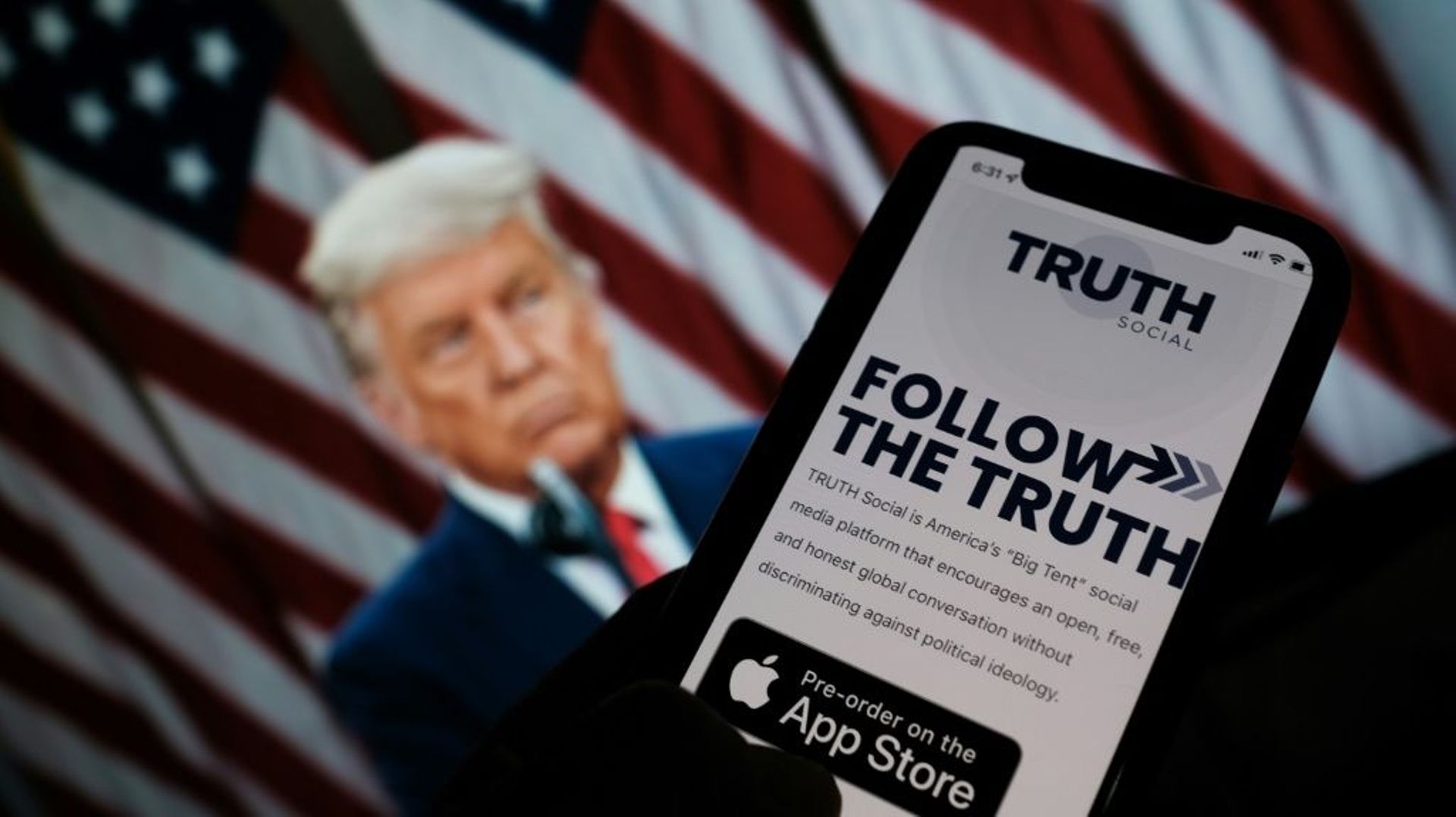 L'application "Truth social" sur l'écran d'un smartphone, devant un portrait de Donald Trump, le 20 octobre 2021 à Los Angeles