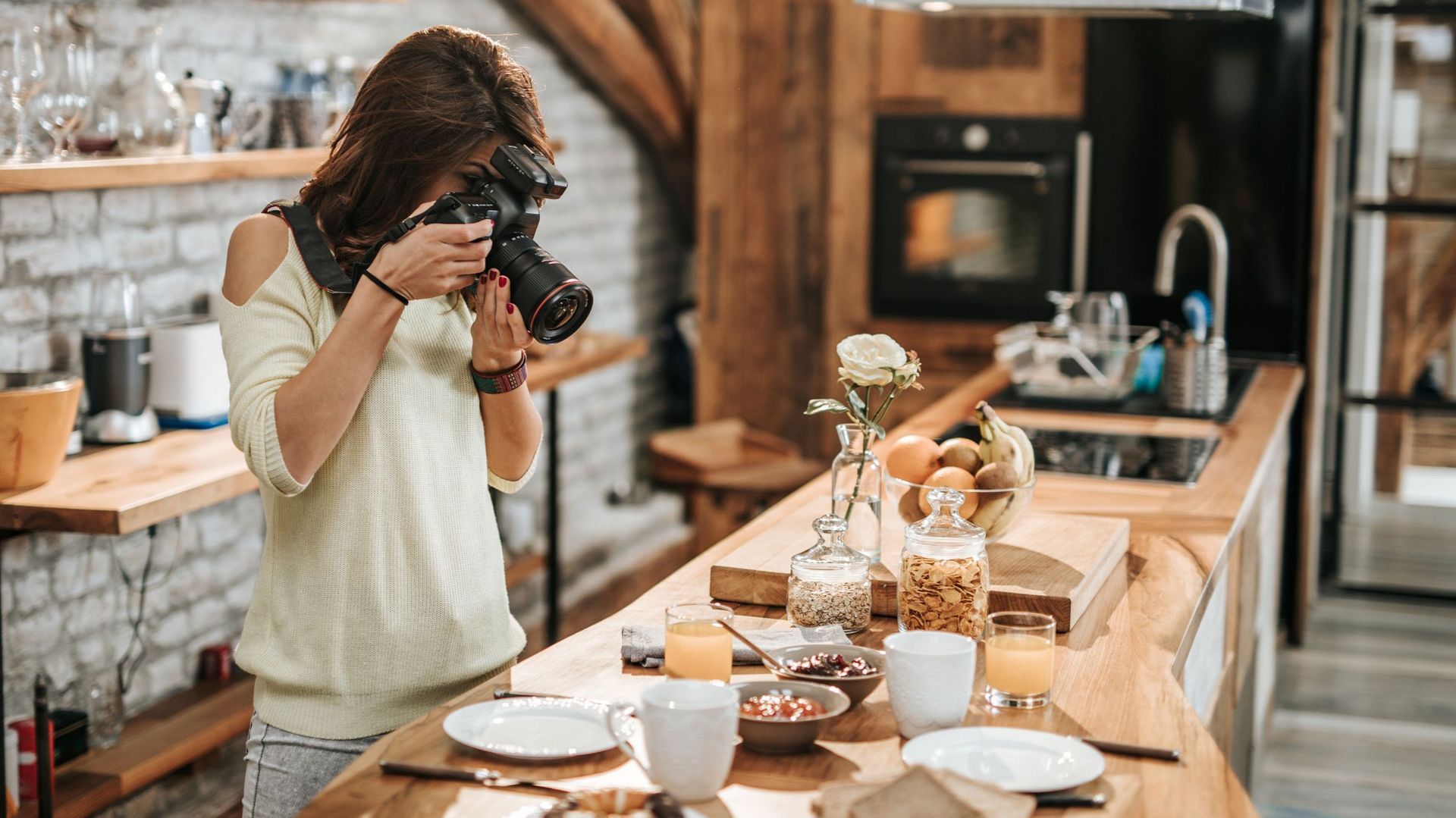 Female photographer taking photos of food at dining table.