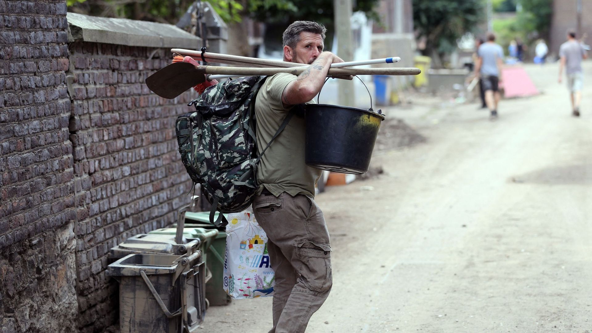 Un homme porte une raclette et un seau alors que les opérations de nettoyage ont commencé à Trooz. Photo d’illustration